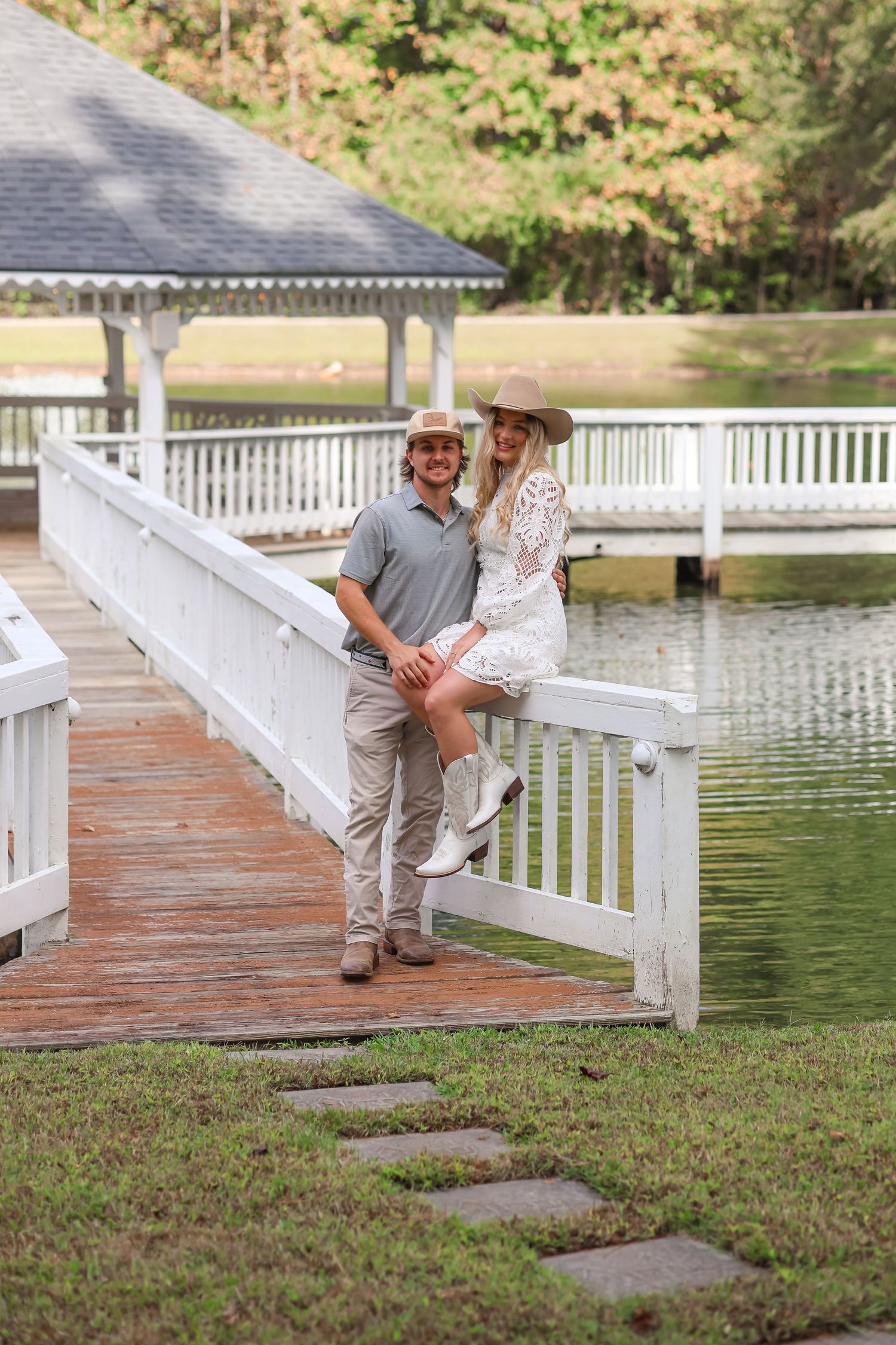 a newly engaged couple standing posed in front of a pond