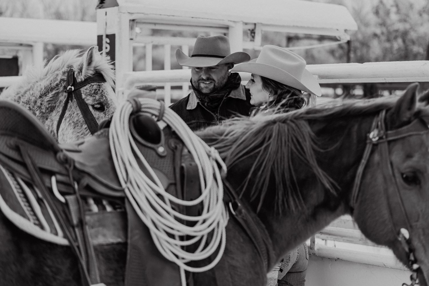 Vintage black and white photo of cowboys with ropes and gear on horseback.