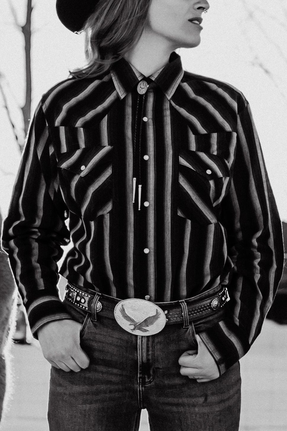 Classic western style with striped shirt, cowboy hat and decorative belt buckle in black and white.