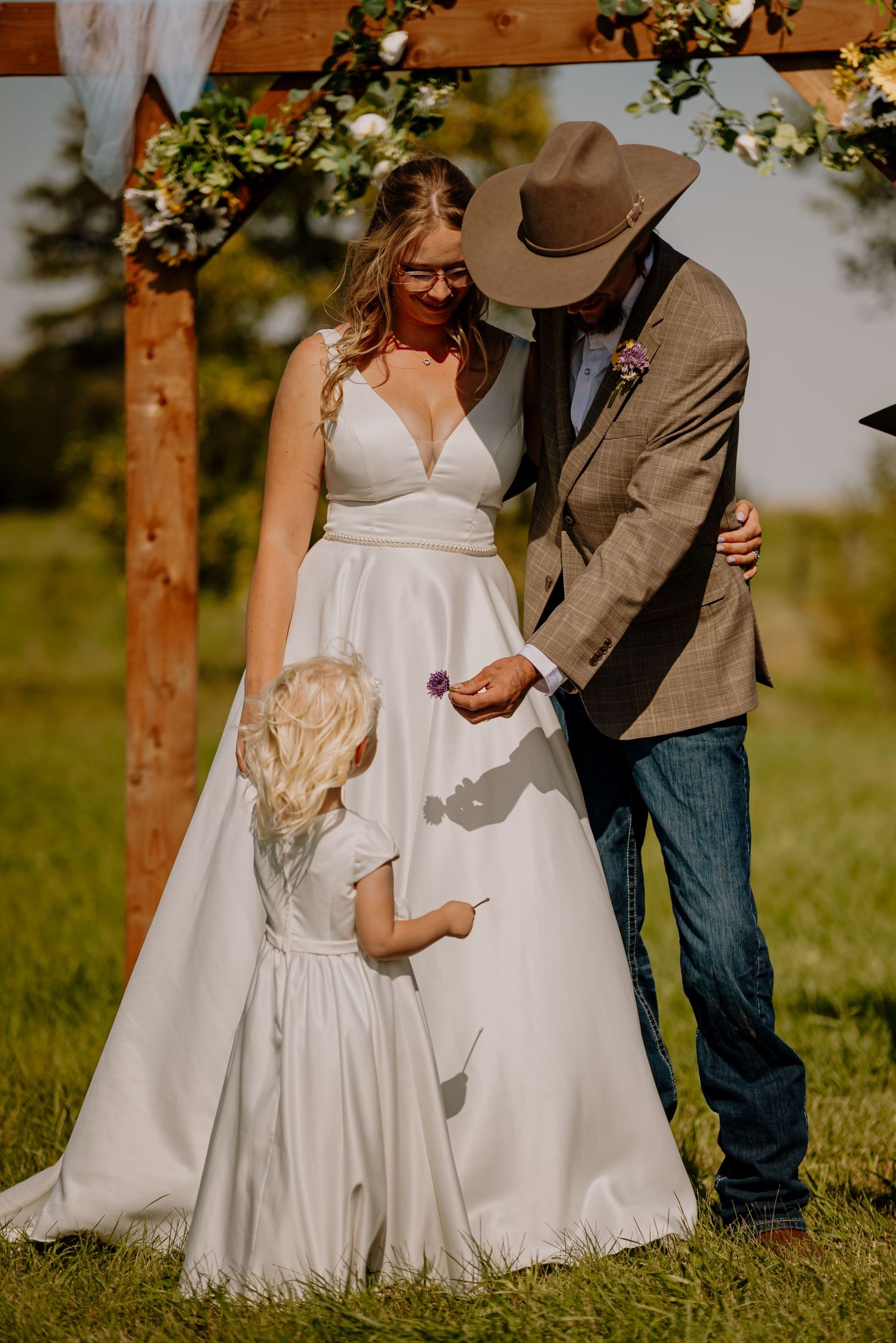 A romantic wedding photo series showing close-up details of a white wedding dress and cowboy boots in a rustic outdoor setting.