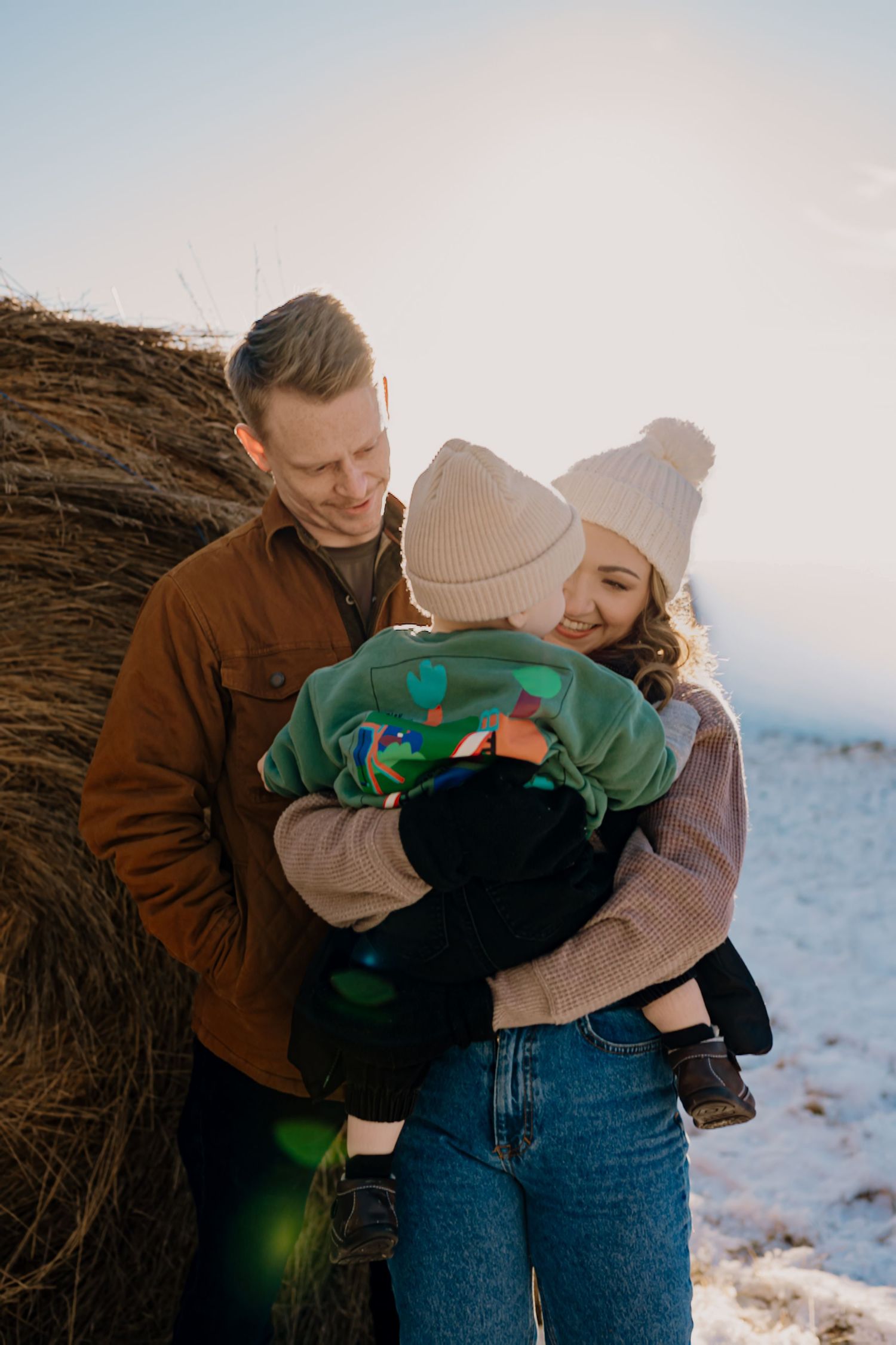 A couple shares tender embraces in a series of romantic winter photos against a snowy landscape backdrop.