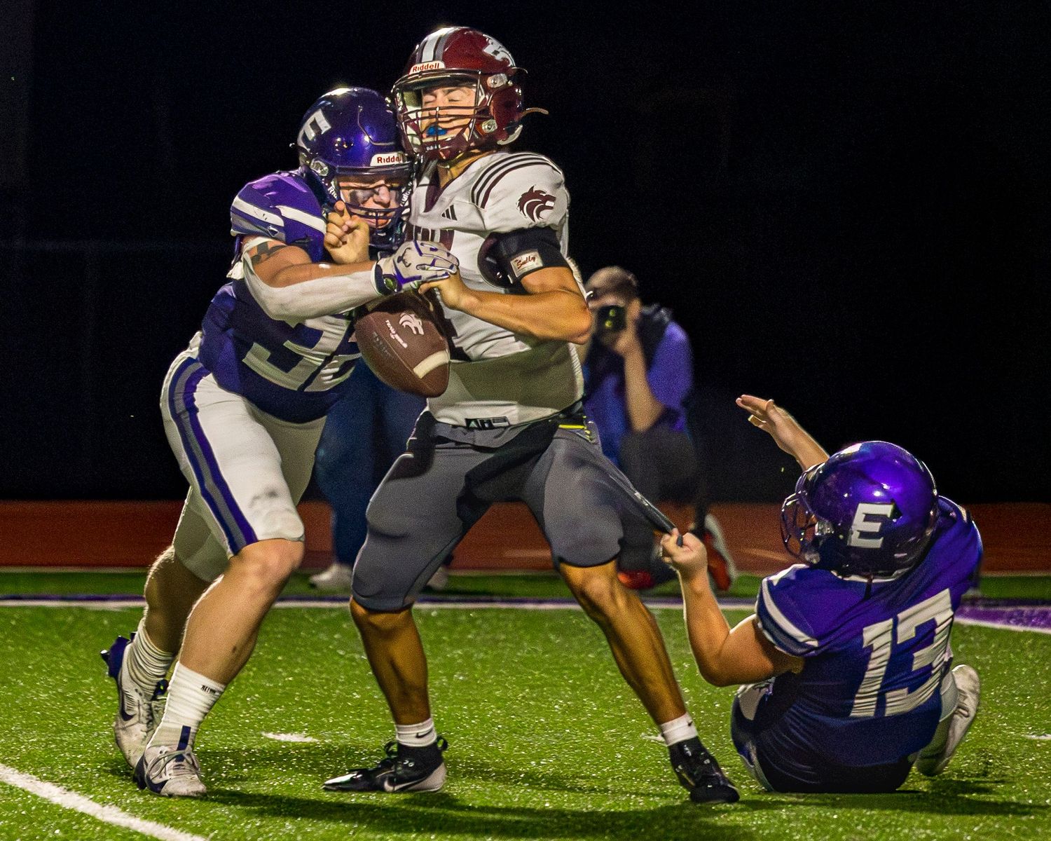 Elkins Elks defensive player Brooks Wills sacks the Lincoln quarterback in a night football game. Photo taken by Trevel Young Photography