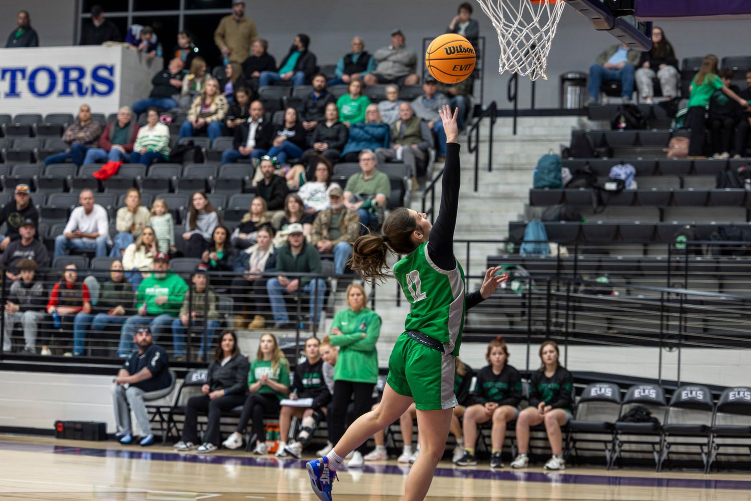 Basketball player in green jersey from Greenland leaps high to make a layup. Photo taken by Trevel Young Photography