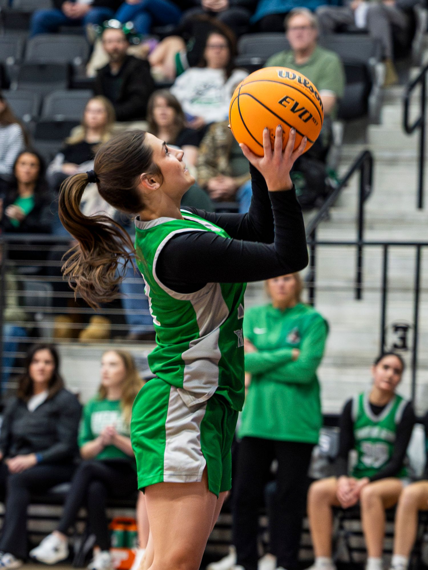 Volleyball player in green jersey jumps high to spike the ball during an intense indoor match.