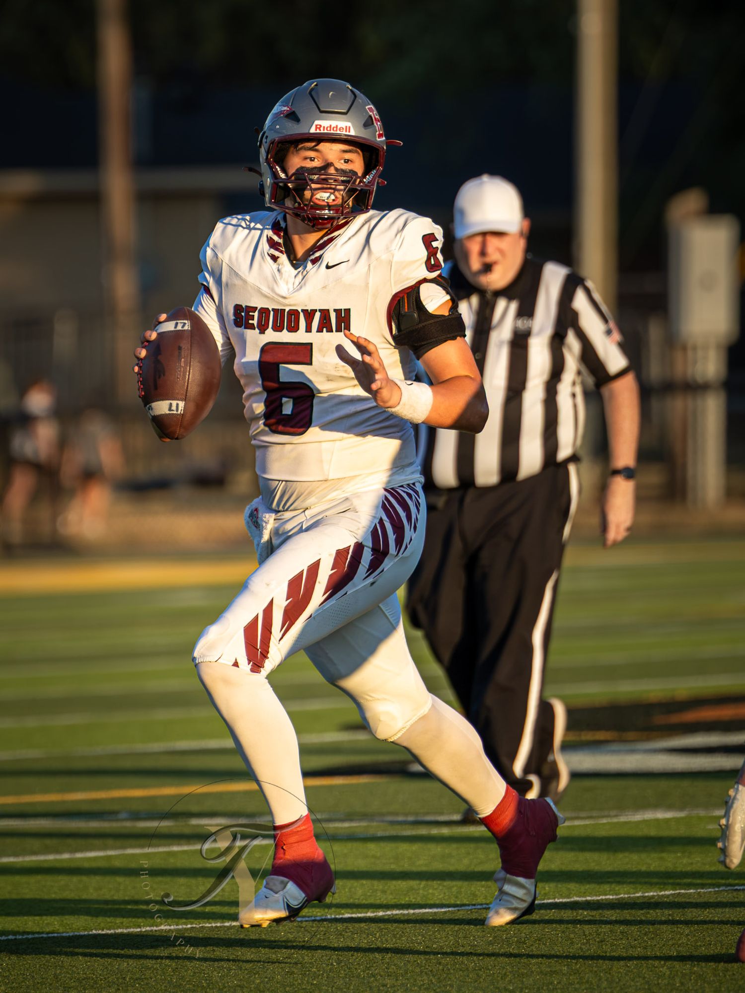Sequoyah football player #6 scrambles with the ball during a game, with a referee visible in the background.