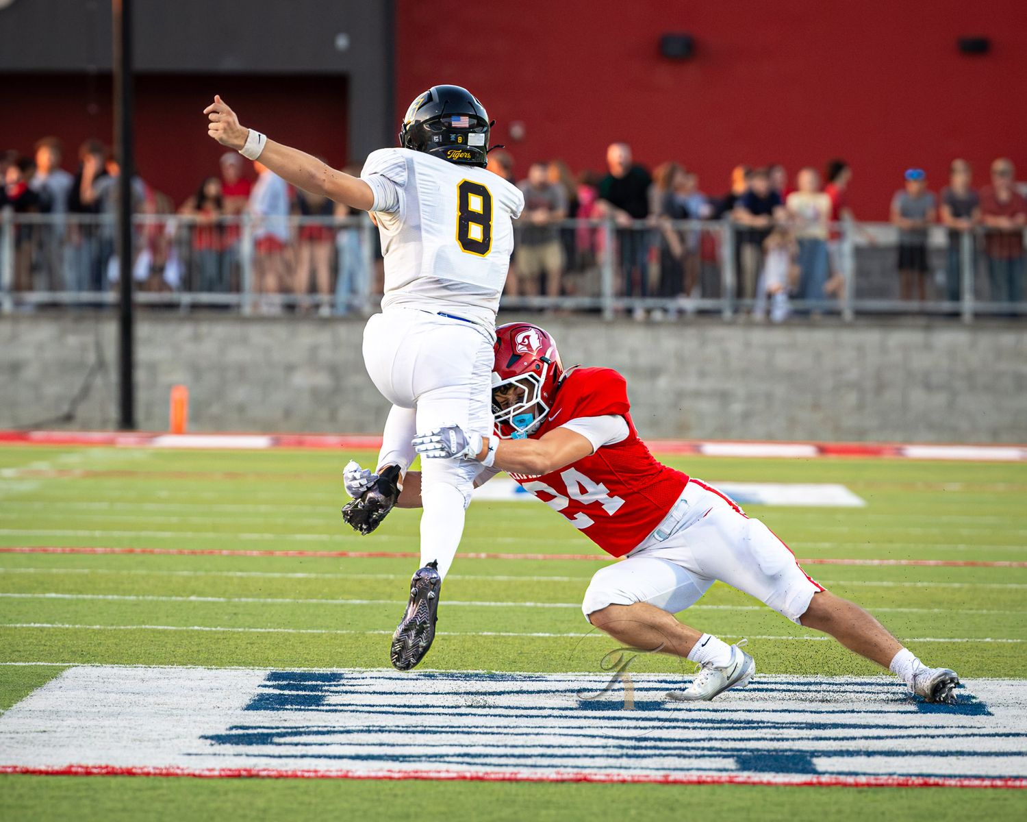 Football player #8 leaps while evading a tackle from a red-uniformed defender during a competitive game.