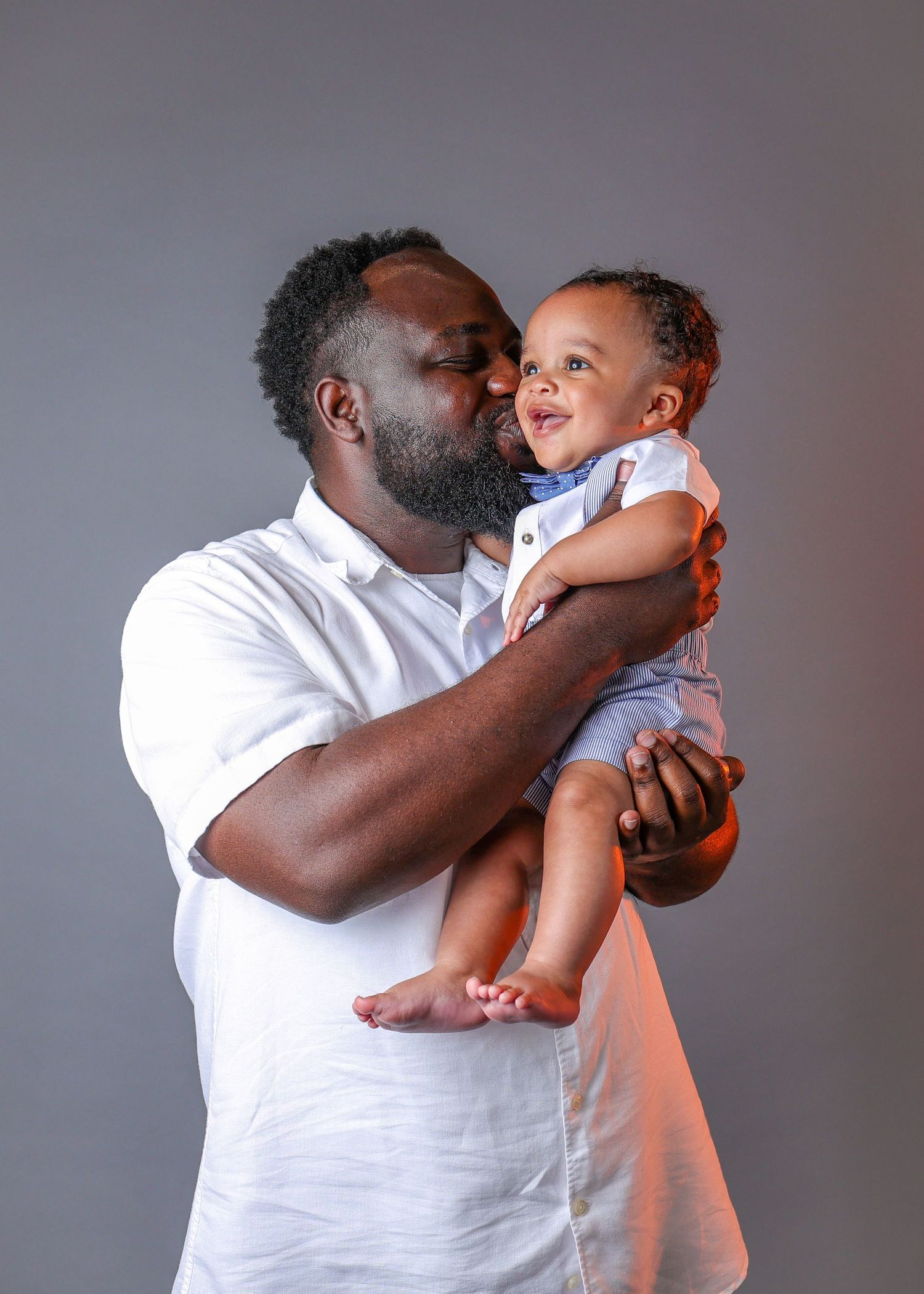 A heartwarming sequence of tender interactions between a parent and young child in matching white outfits.