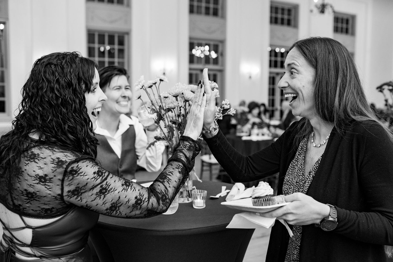 Wedding reception guests sharing animated conversations around elegantly decorated dining tables.