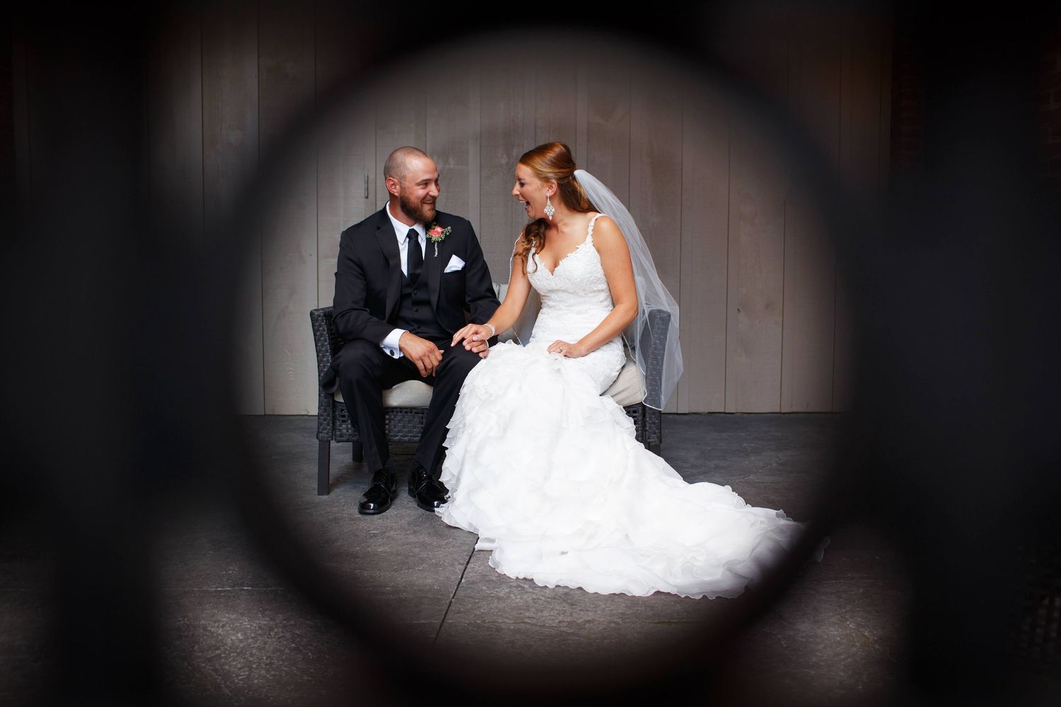 Artistic vignette portrait of newlyweds sitting together in formal attire.