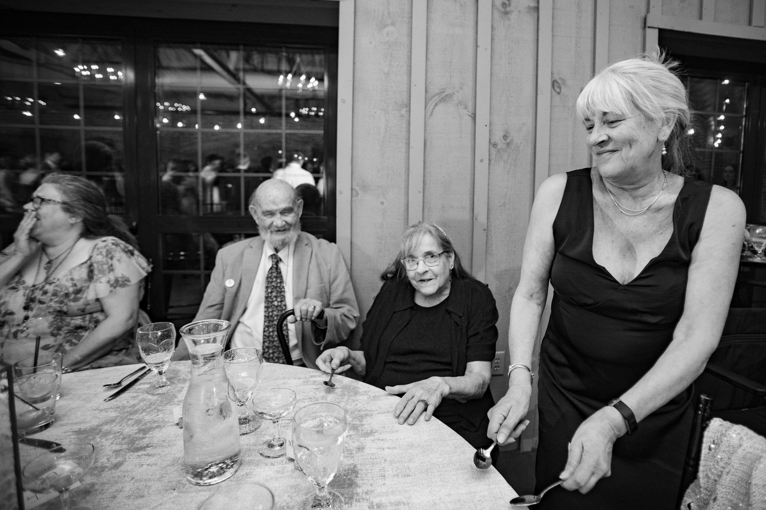 Black and white photo of elderly guests seated at a formal dinner table at an event.