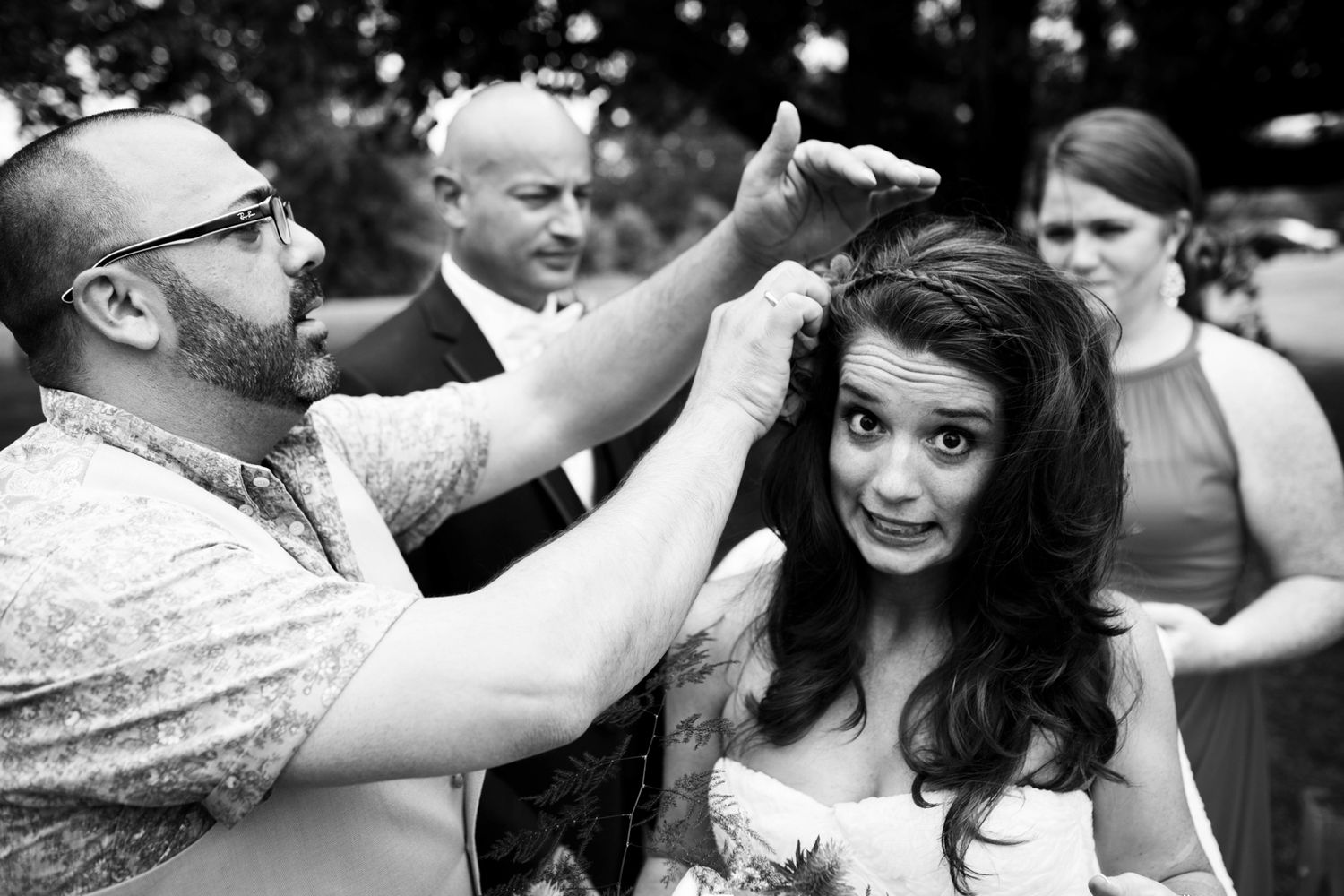 A bride is getting her hair touched up before a reception, this is a black and white image, documentary style