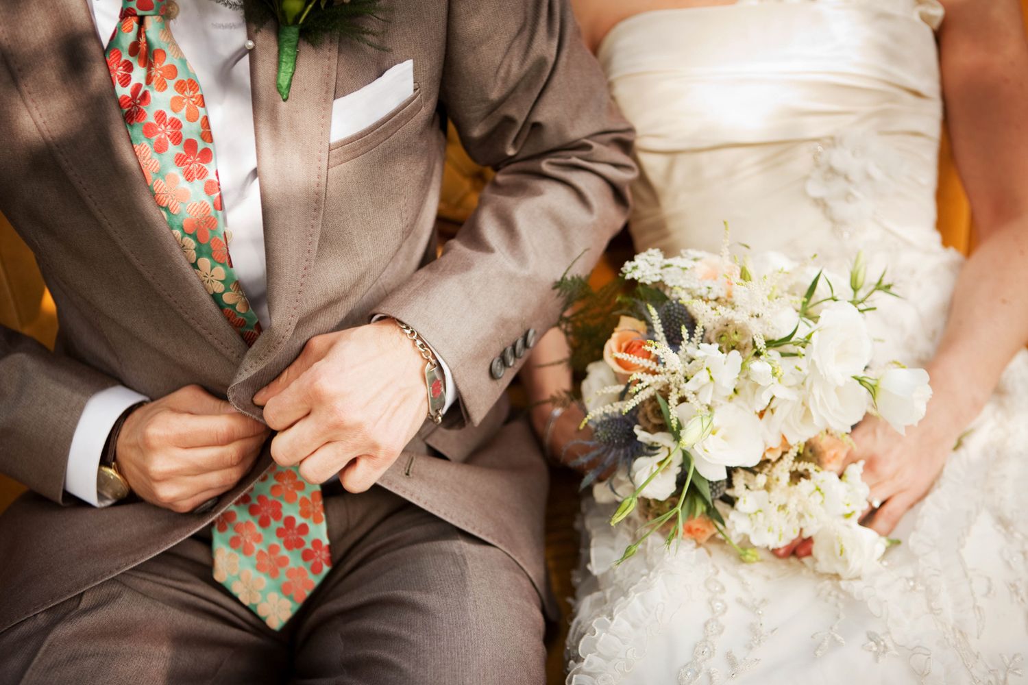 a detail shot of a brown suit on a groom and a bride's flowers