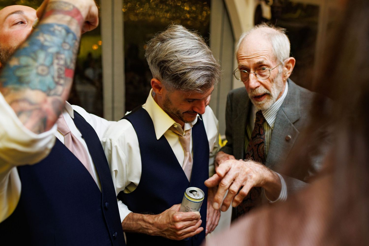 Candid shots of reception guests engaged in conversation wearing formal suits and glasses.
