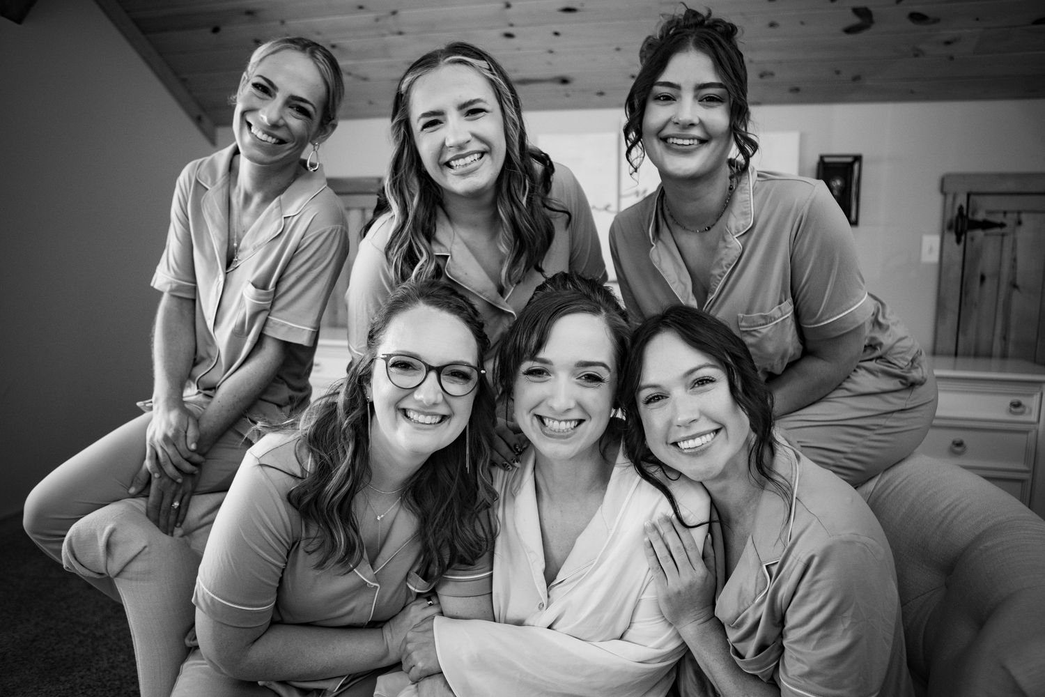 Black and white photo of six smiling bridesmaids posing together in robes before a wedding ceremony.