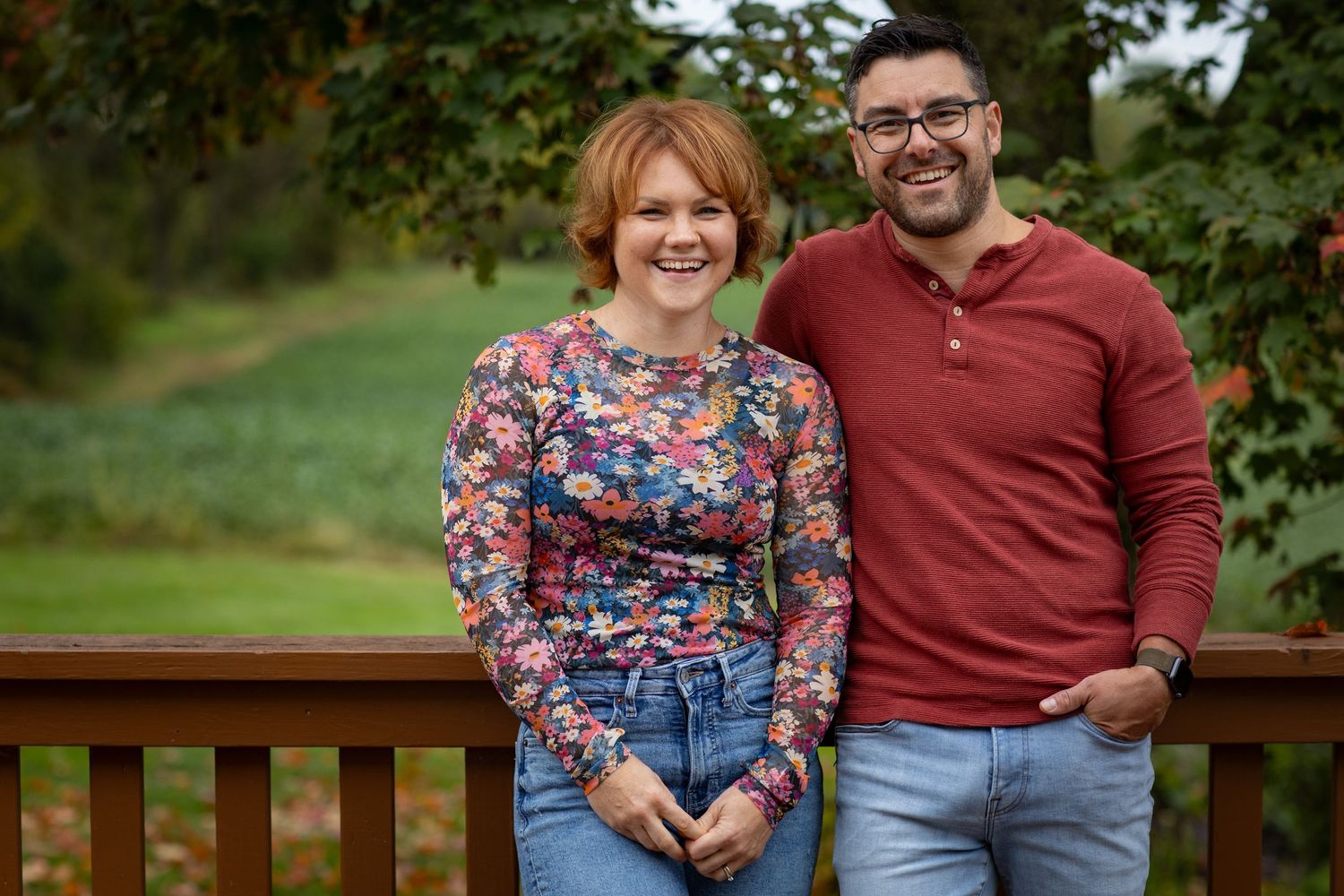A couple shares a romantic moment together on a wooden bench in an autumn setting.