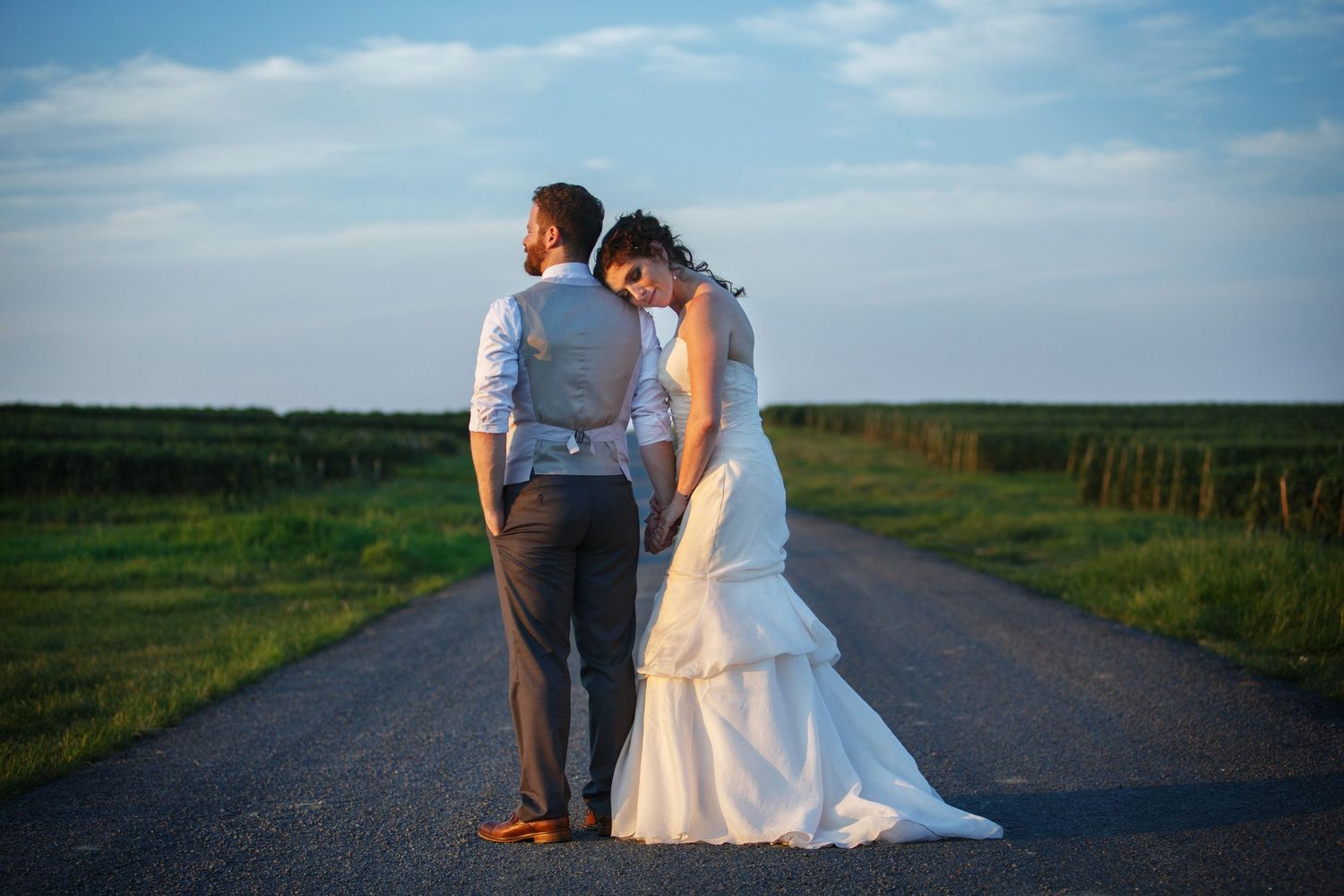 Sunset portrait of couple standing on rural road with dramatic sky.