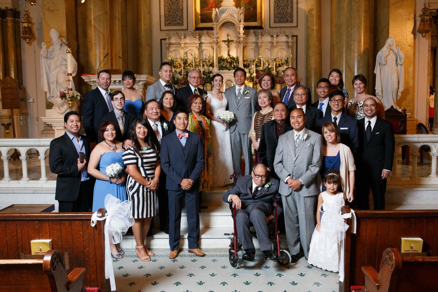 Wedding party members stand together for formal portraits inside an ornate church sanctuary.