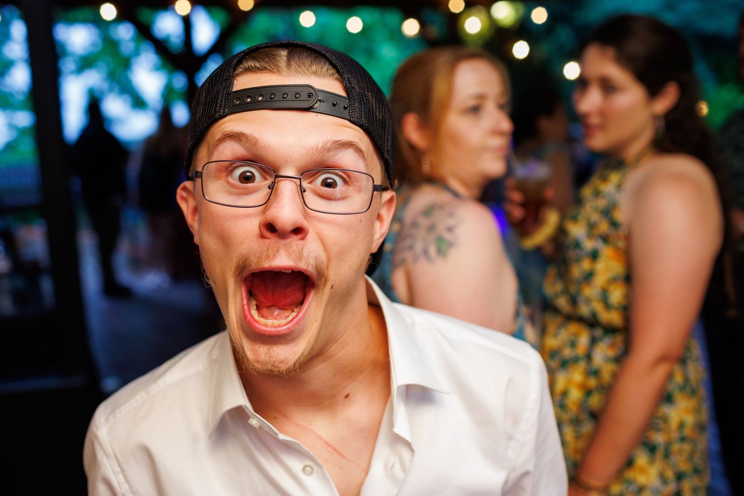 Excited young man making a funny face at an outdoor wedding reception party.