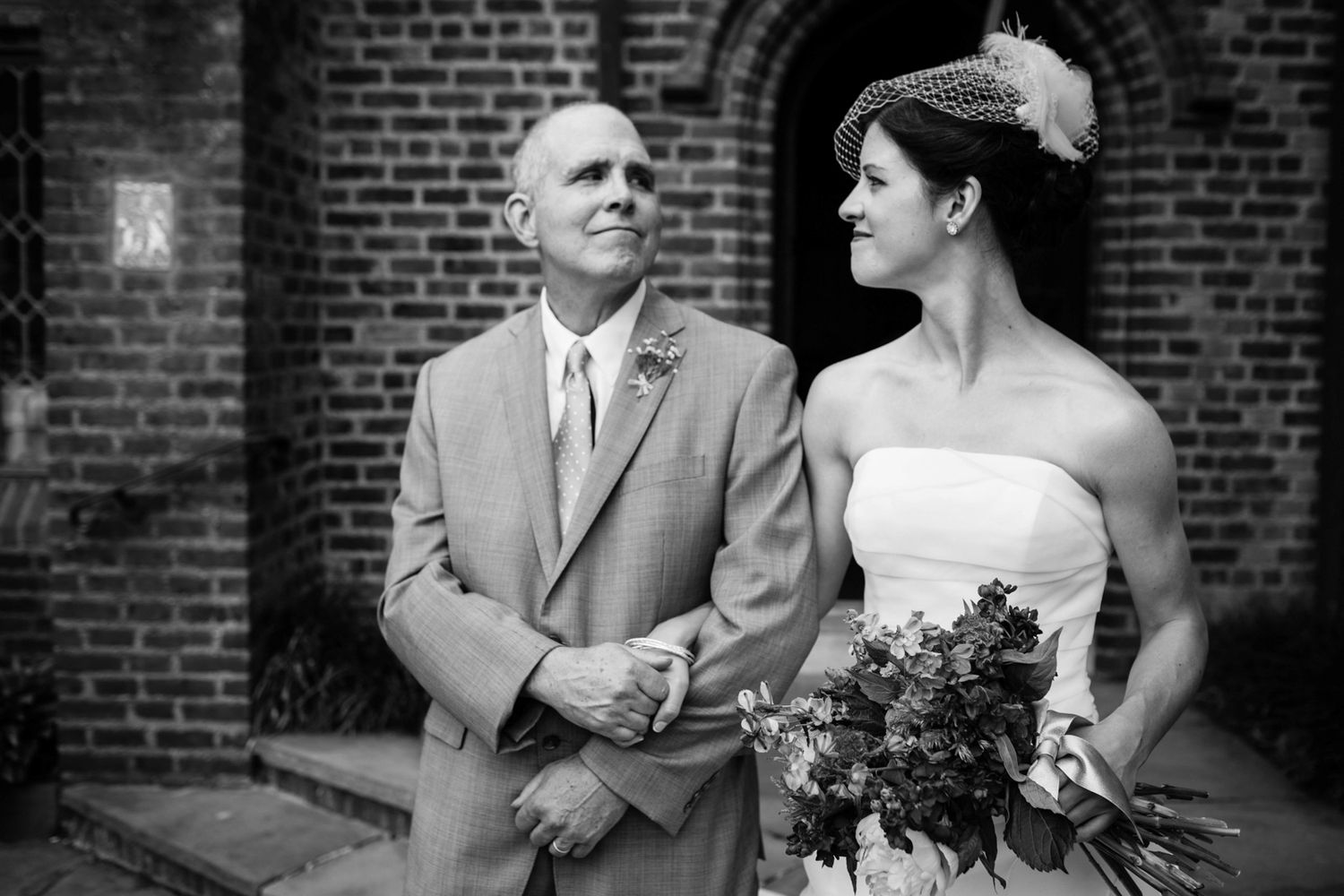 Elegant black and white portrait against a brick wall backdrop during a wedding ceremony.