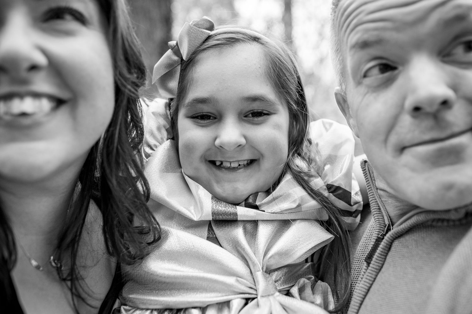 A black and white close-up portrait of a happy family smiling together outdoors.