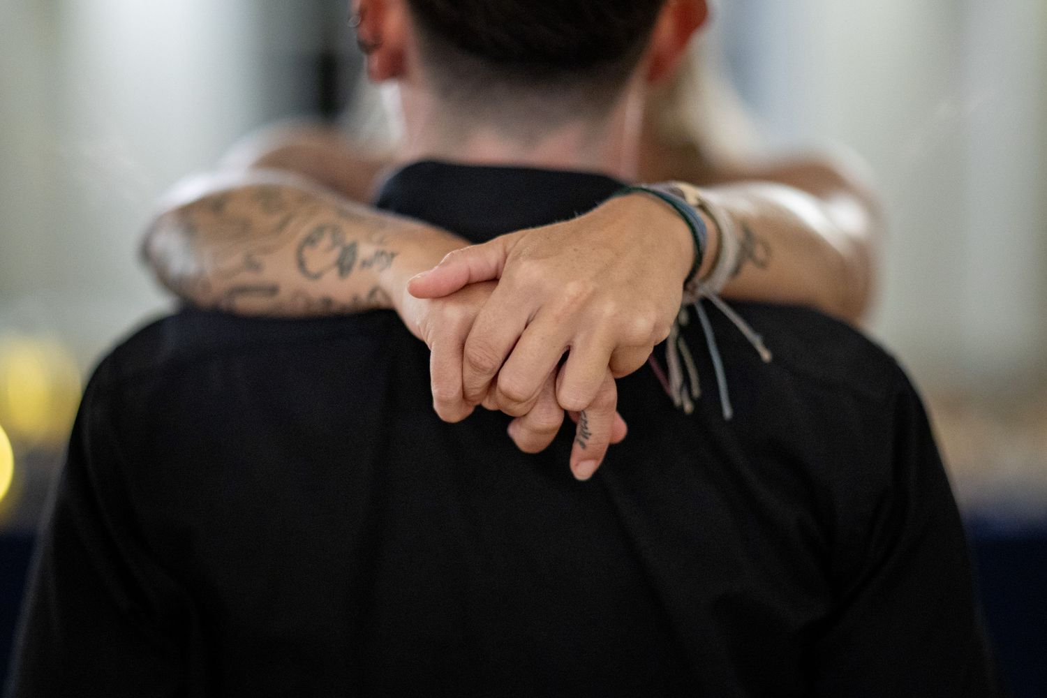 Close-up view of person's back showing tattoo and black clothing at event.