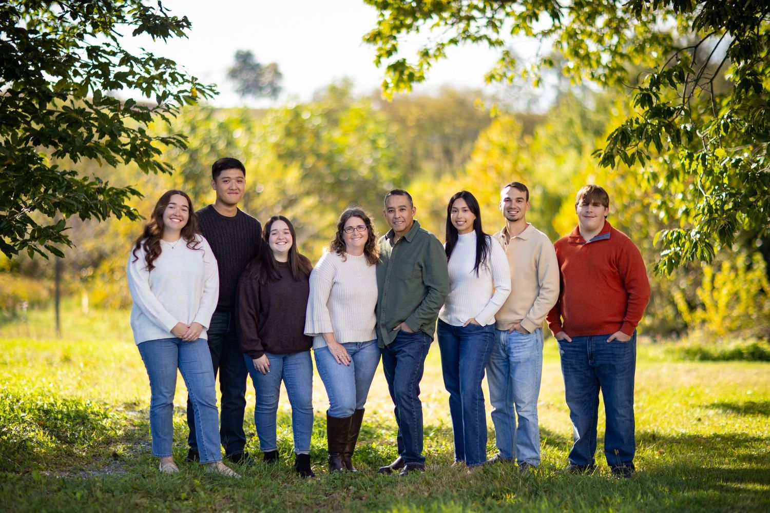 A casual group photo of people sitting in a row outdoors wearing coordinated blue and neutral colored clothing.