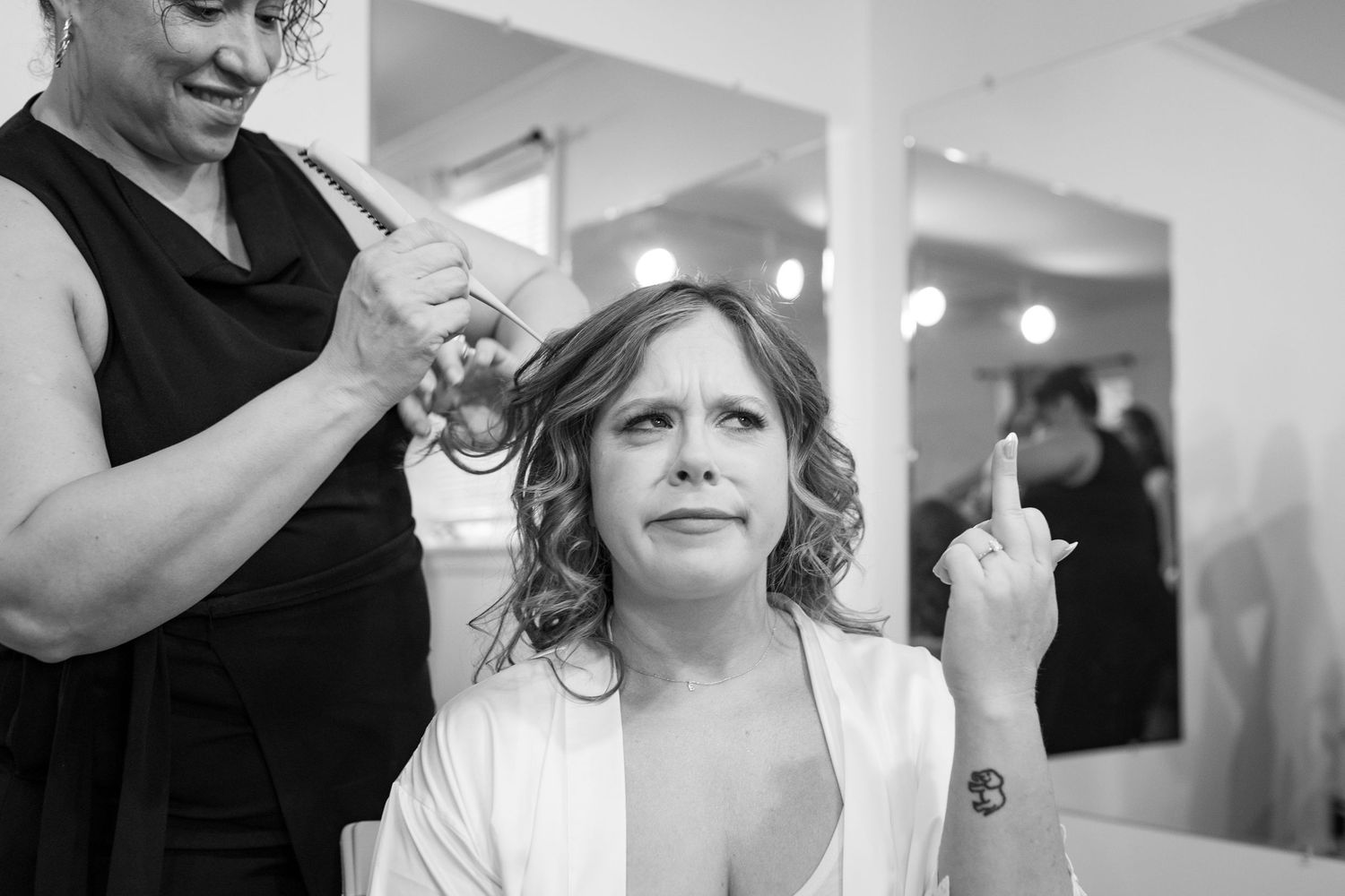 Bride making a funny face while getting hair styled before wedding ceremony.