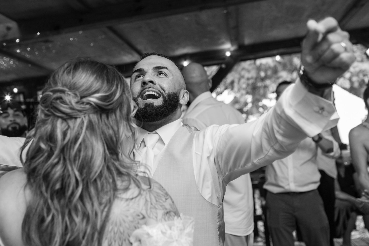 Bride and groom dancing joyfully together under sparkling lights at their wedding reception.