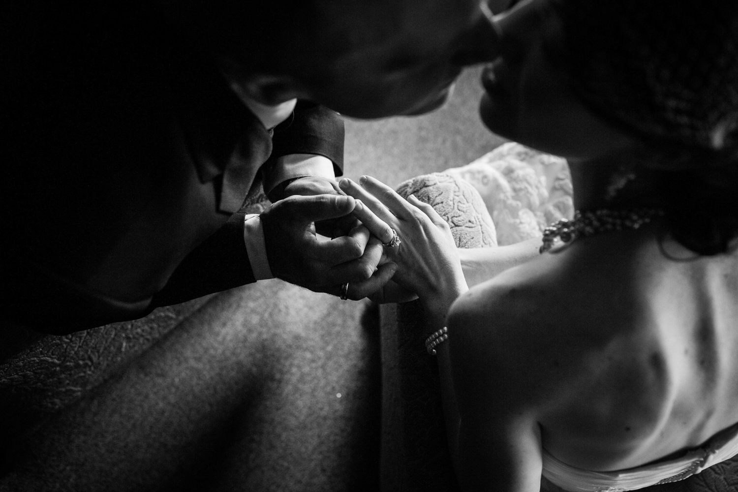 close up photo of couple kissing with rings on and holding hands