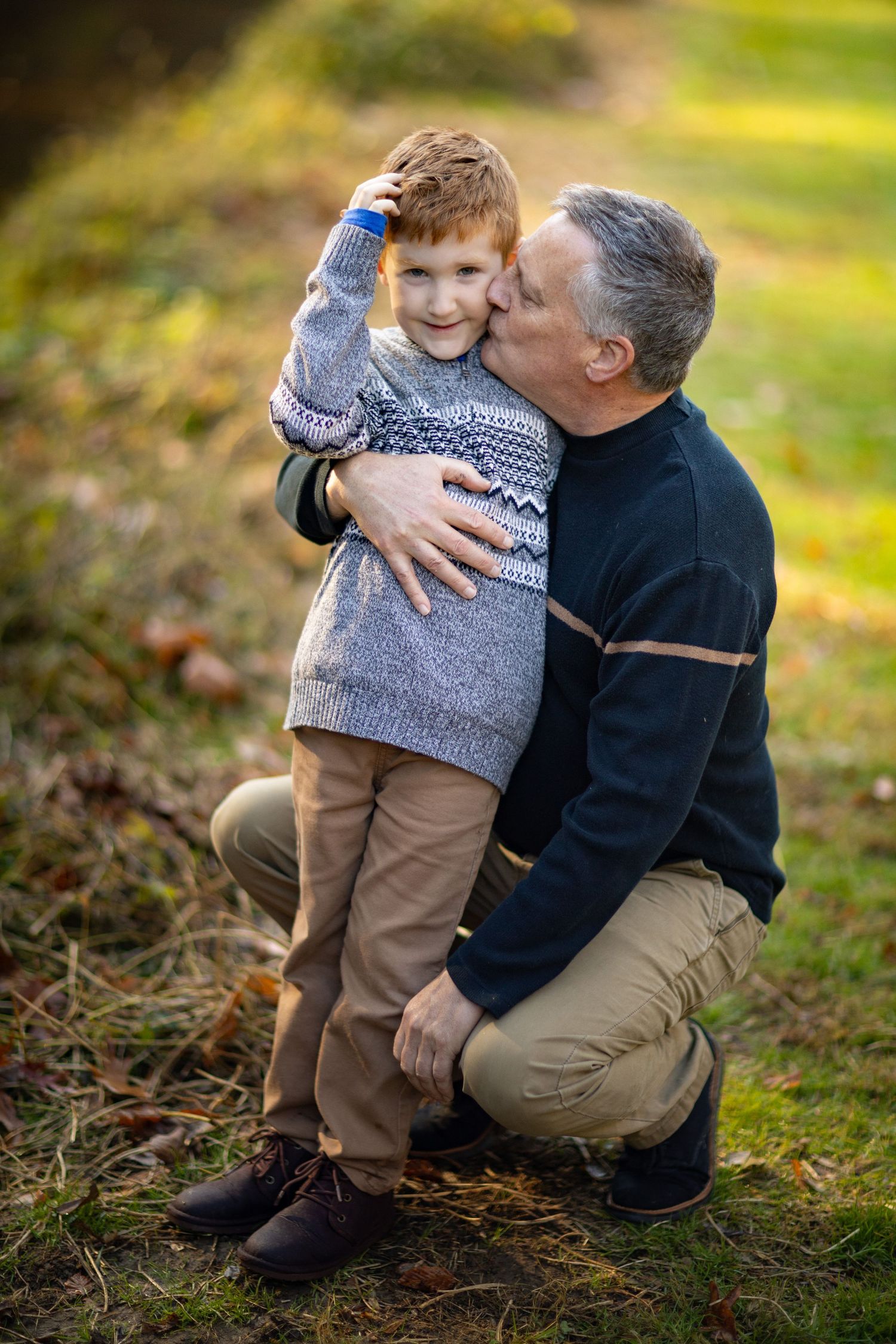 A touching moment captured between two people on fallen autumn leaves in soft natural lighting.