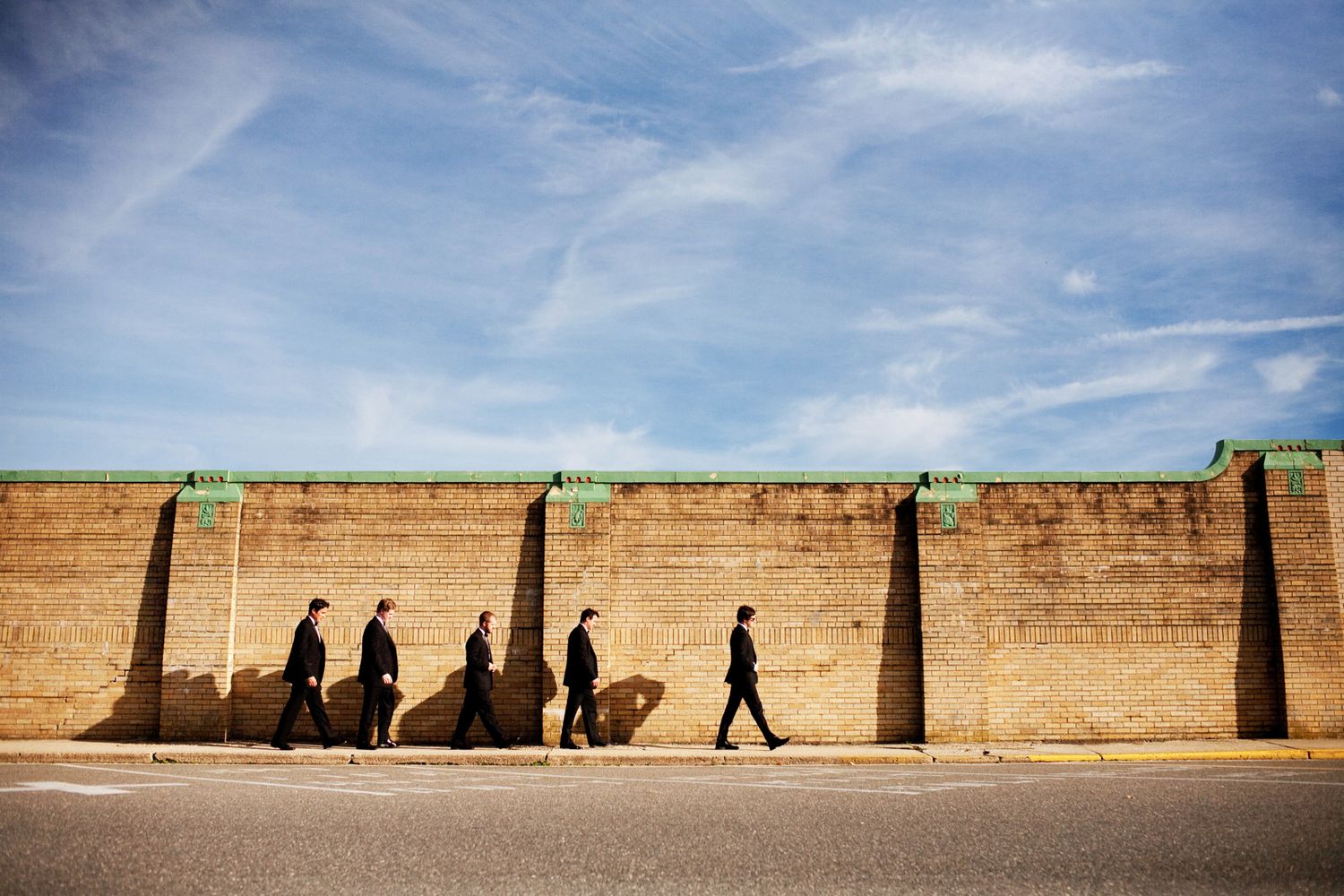 a groom and his groomsmen walk along a sea wall