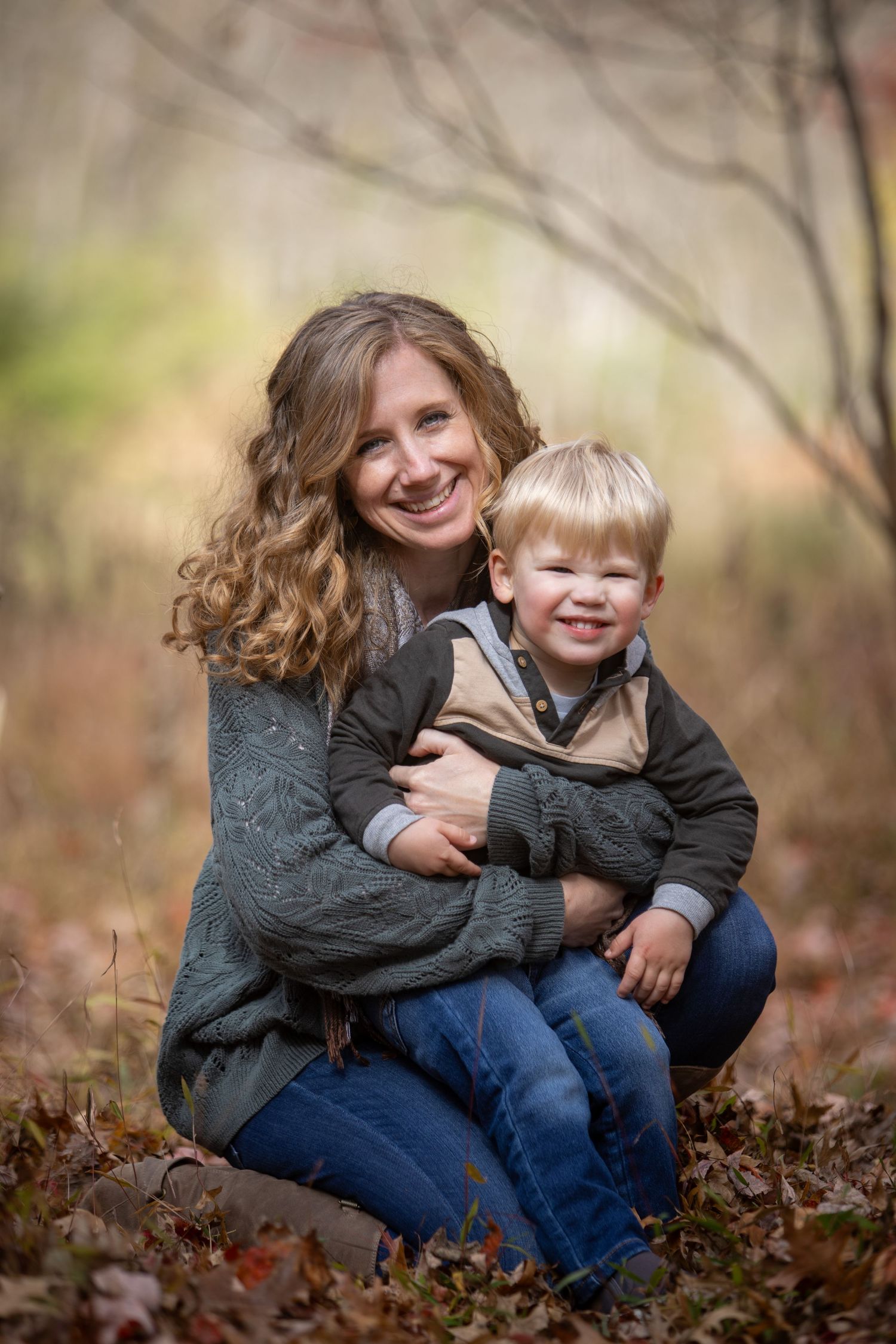 Two people share joyful moments while sitting together in fallen autumn leaves on a crisp fall day.