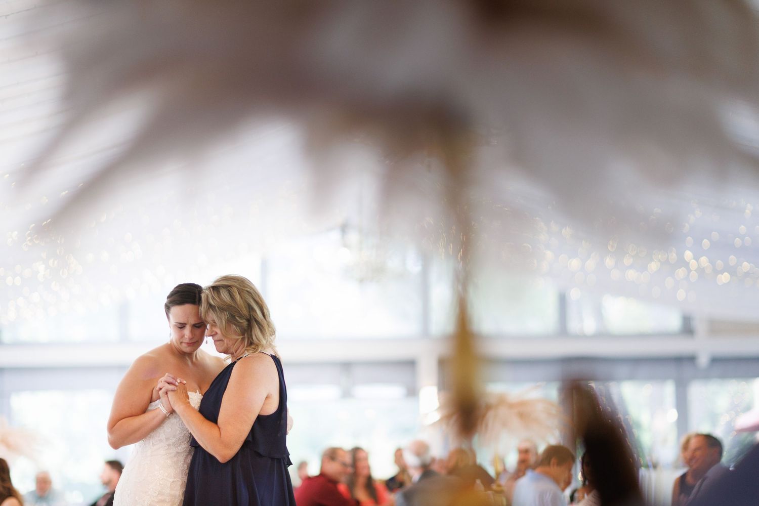 Wedding reception scene in a white tent with soft focus lighting.