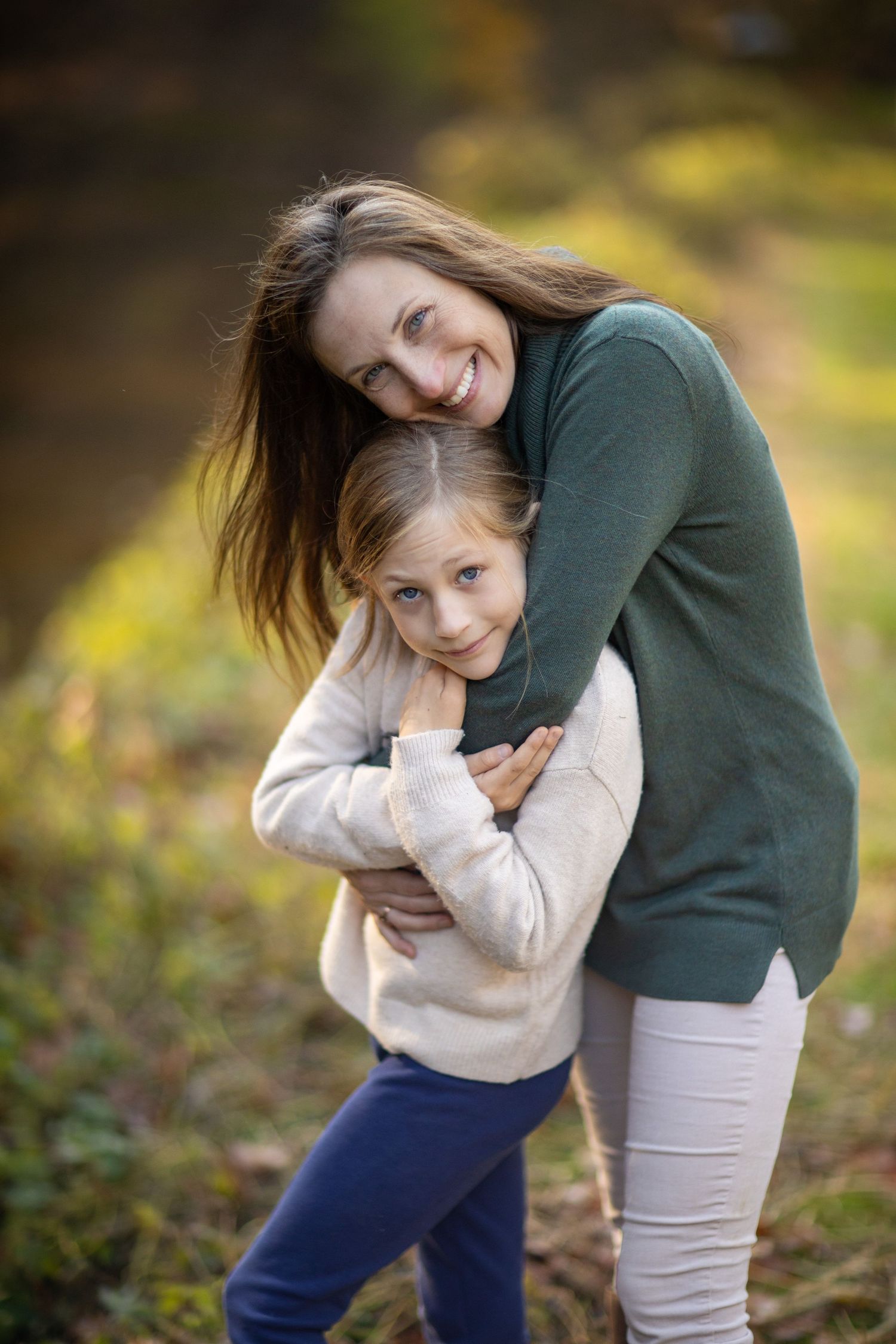 Person in green sweater hugs and plays with someone in casual fall attire.