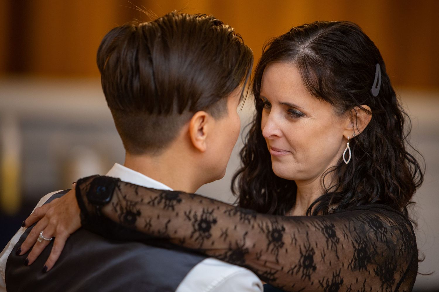People in formal attire having intimate conversations at an indoor event.