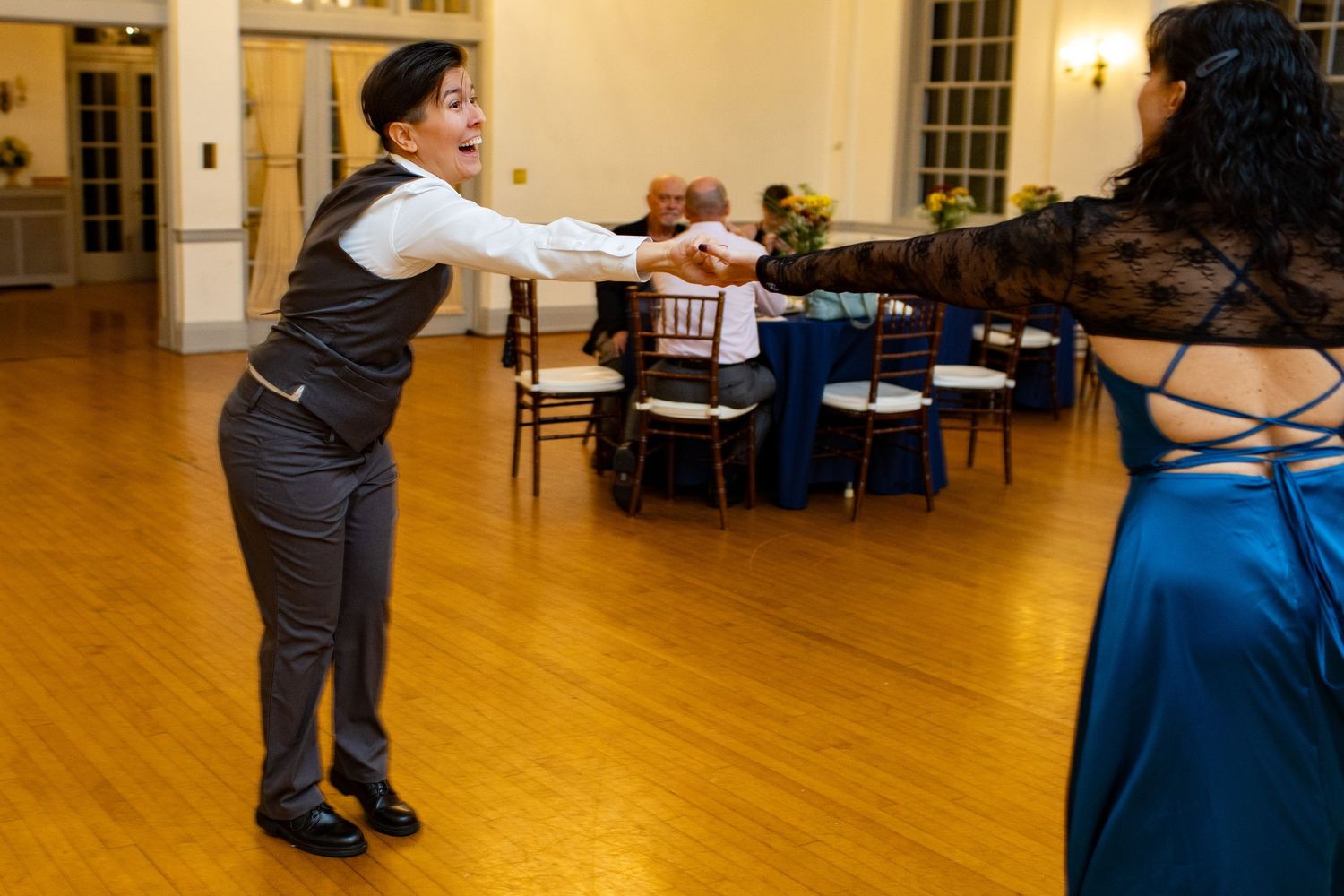 People dancing on wooden floor in spacious reception hall.