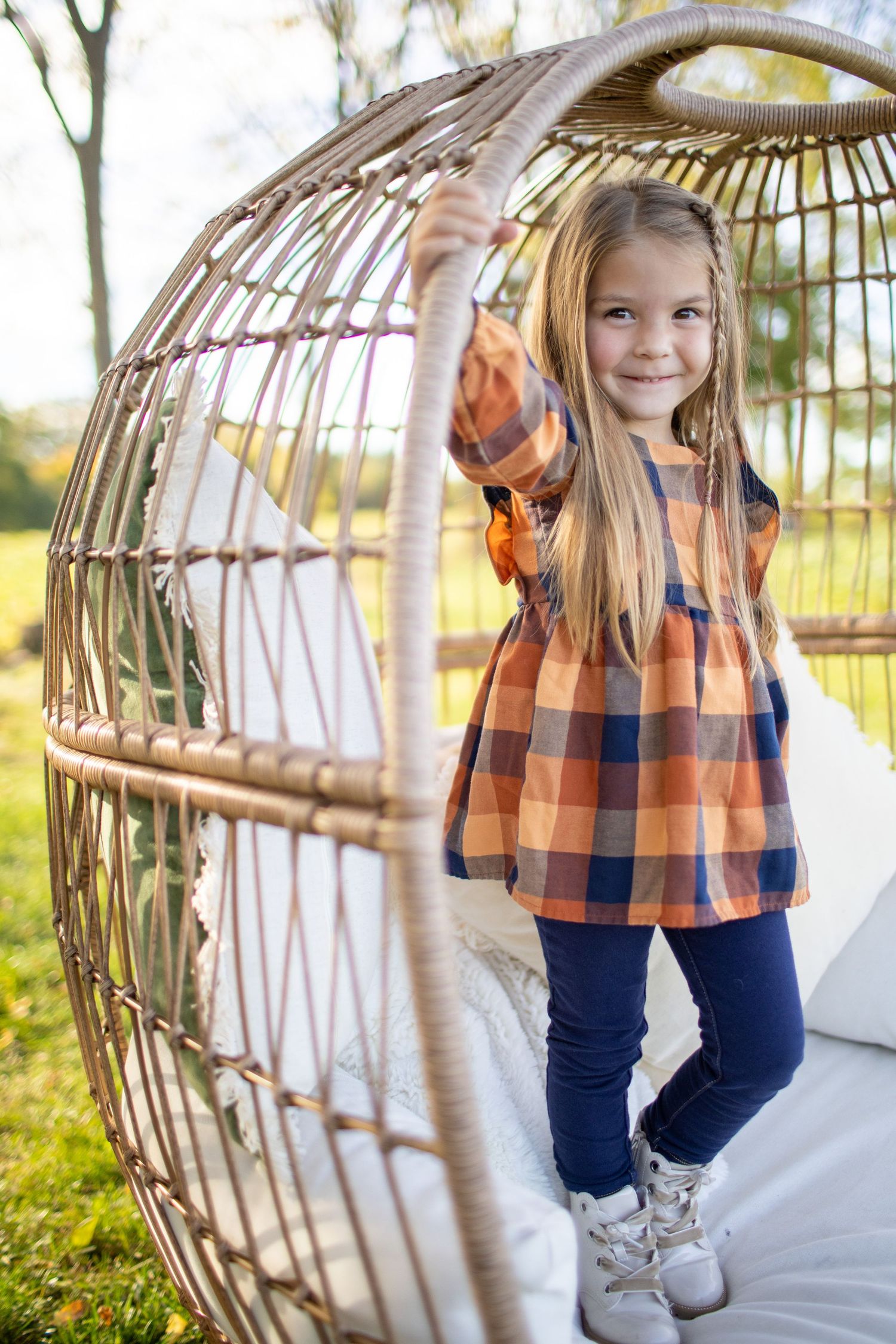 A series of playful poses in a wicker hanging chair against a sunny outdoor backdrop.