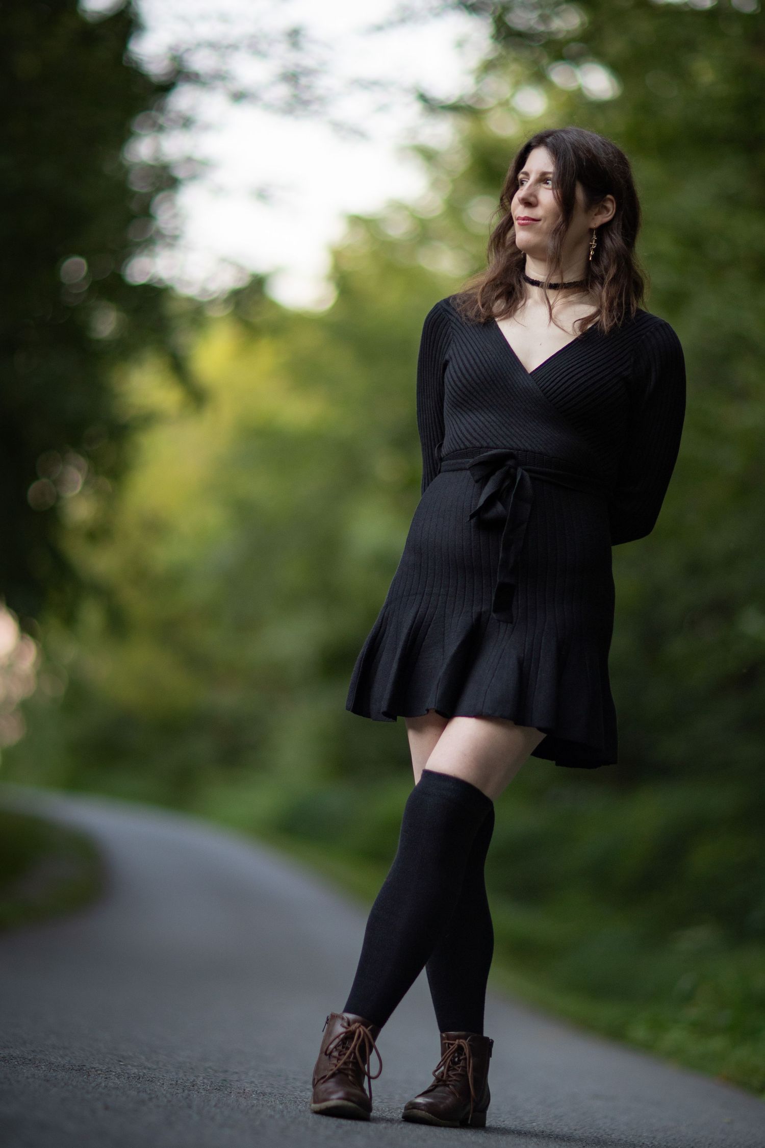 A sequence of full body poses featuring someone in a black dress and boots on an outdoor path.