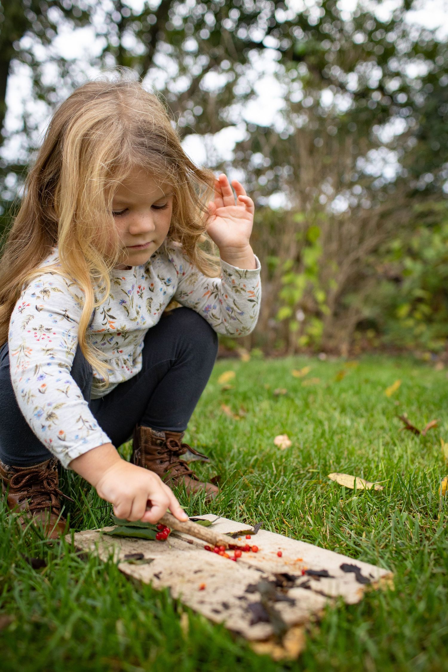 Child exploring and playing with objects in green grass during autumn.