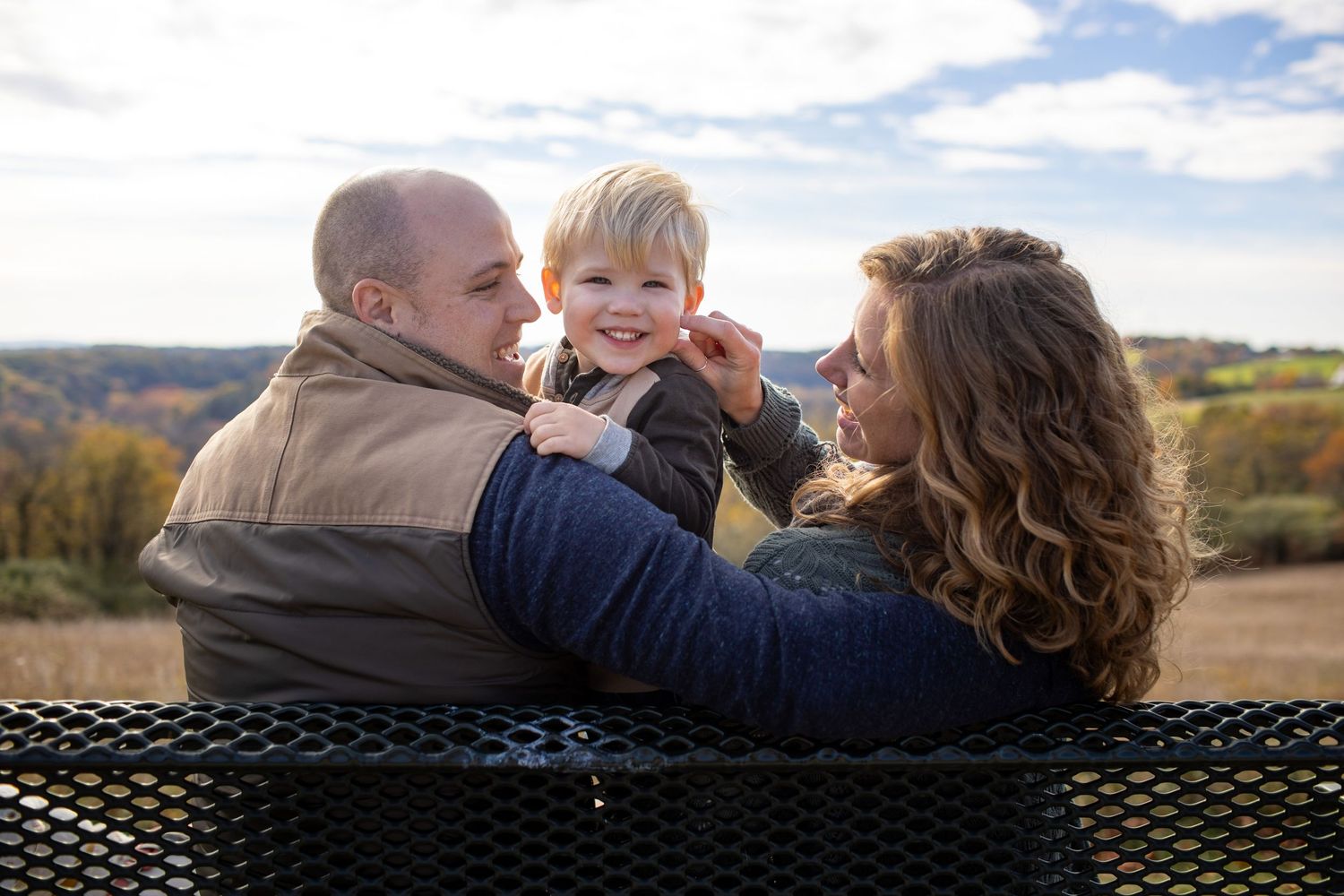 Family enjoying a tender moment together while sitting on a grassy hillside during golden hour.