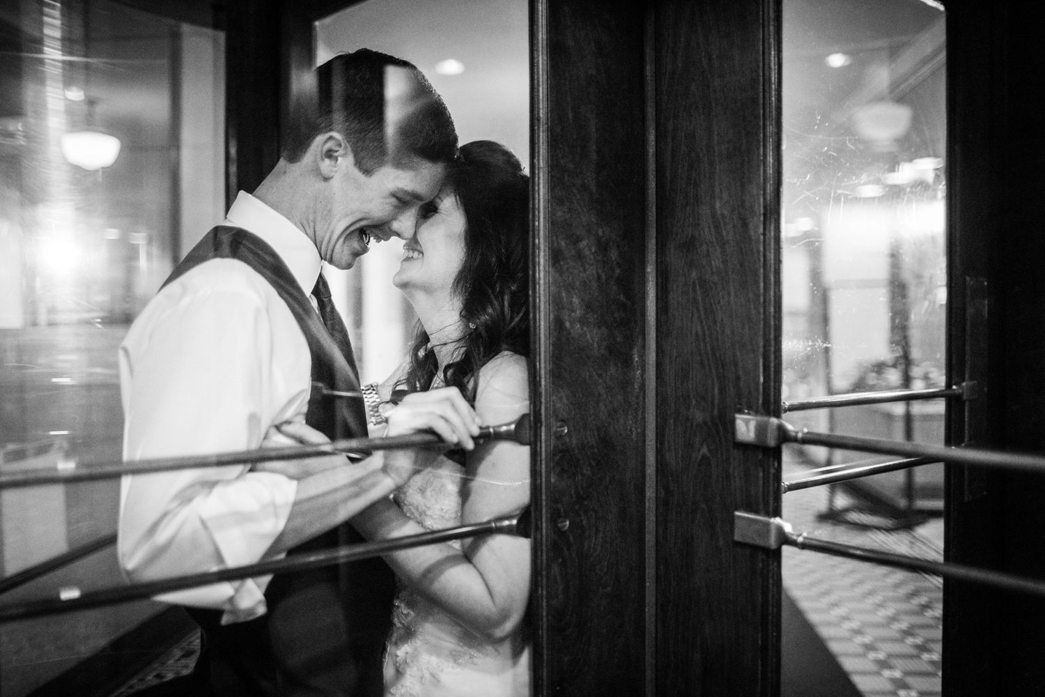 bride and groom in a revolving door kissing