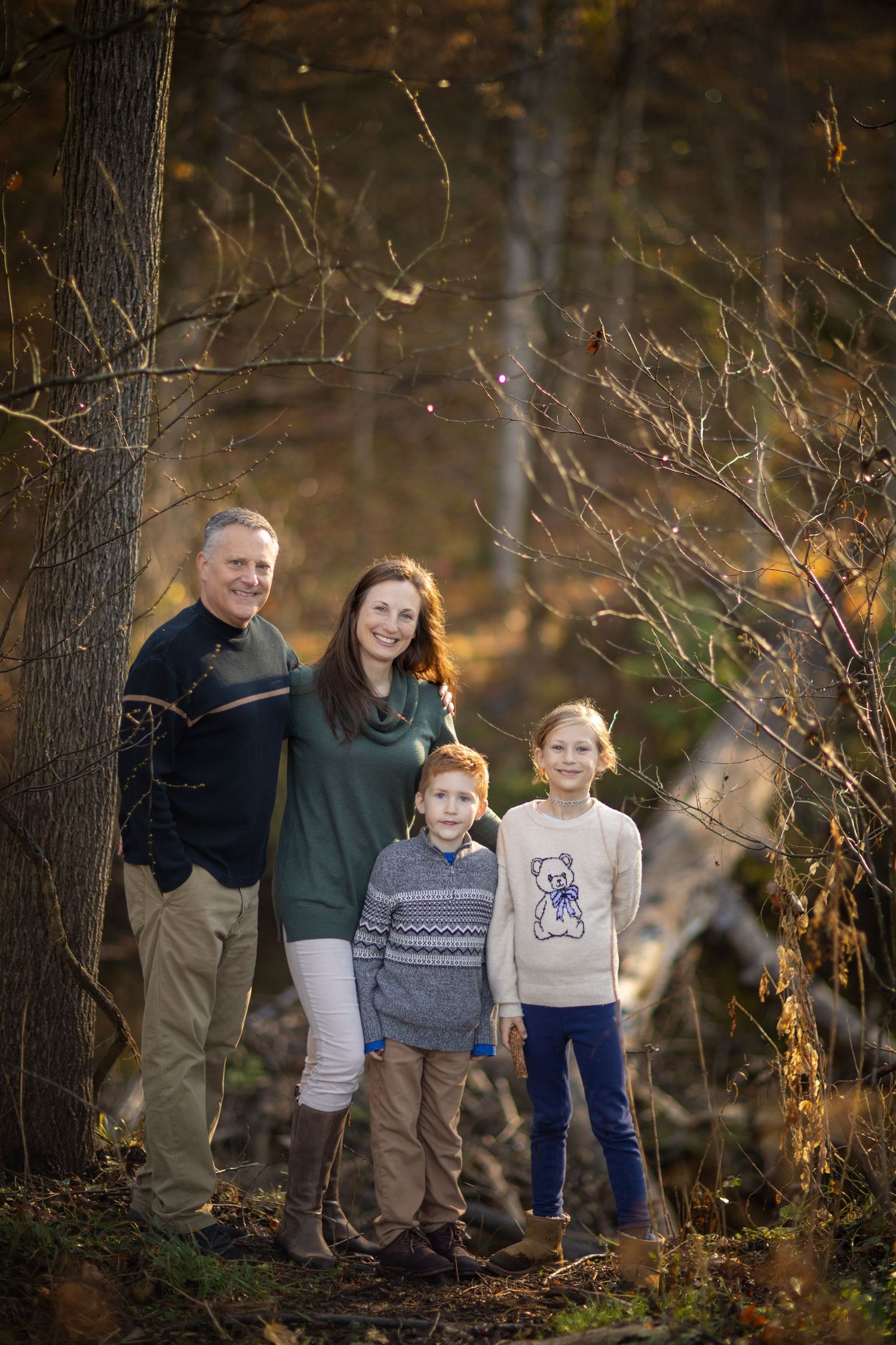 Group poses together among trees during fall outdoor photo session.