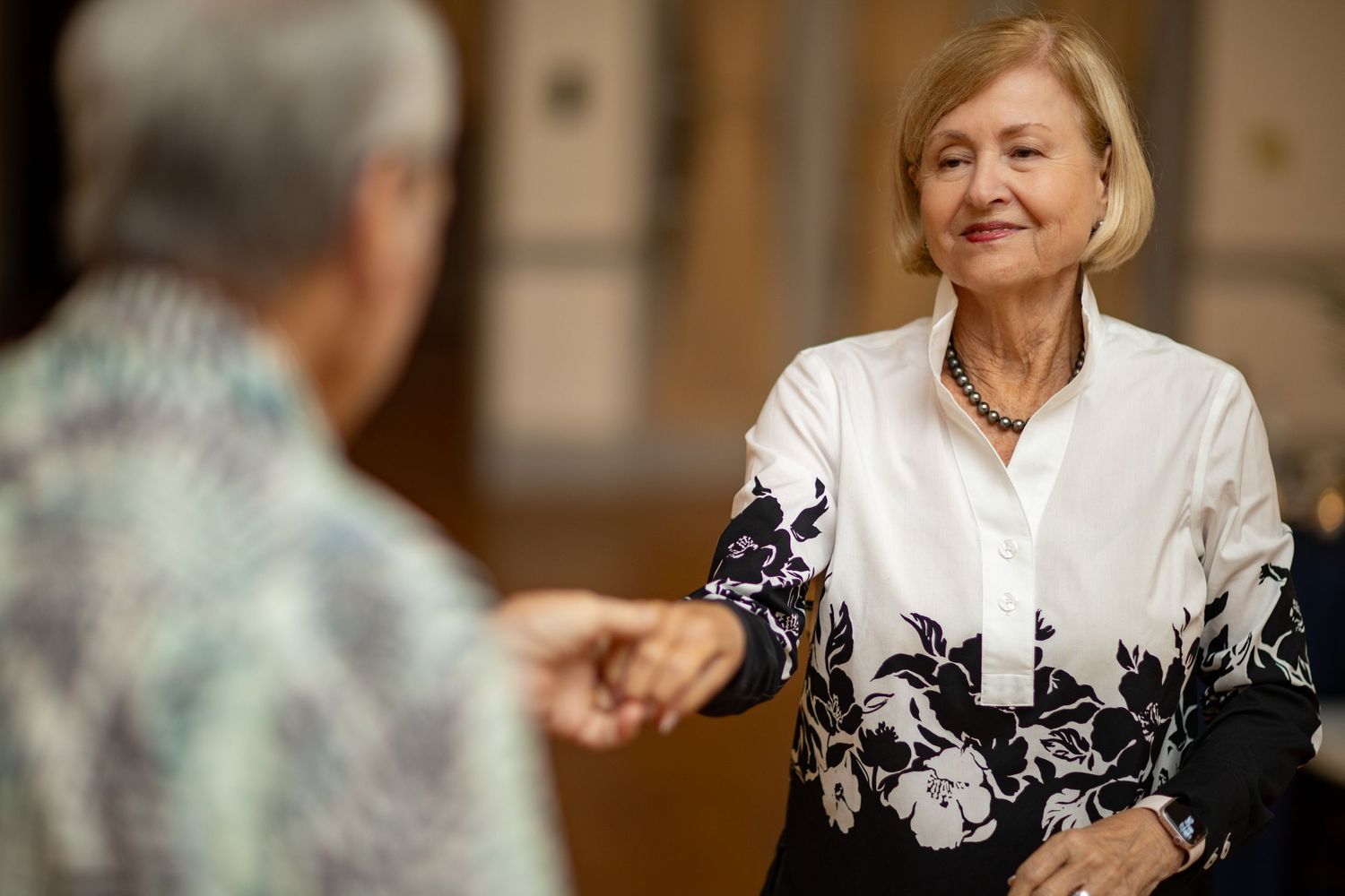 People in formal attire engaged in conversation at evening social gathering.