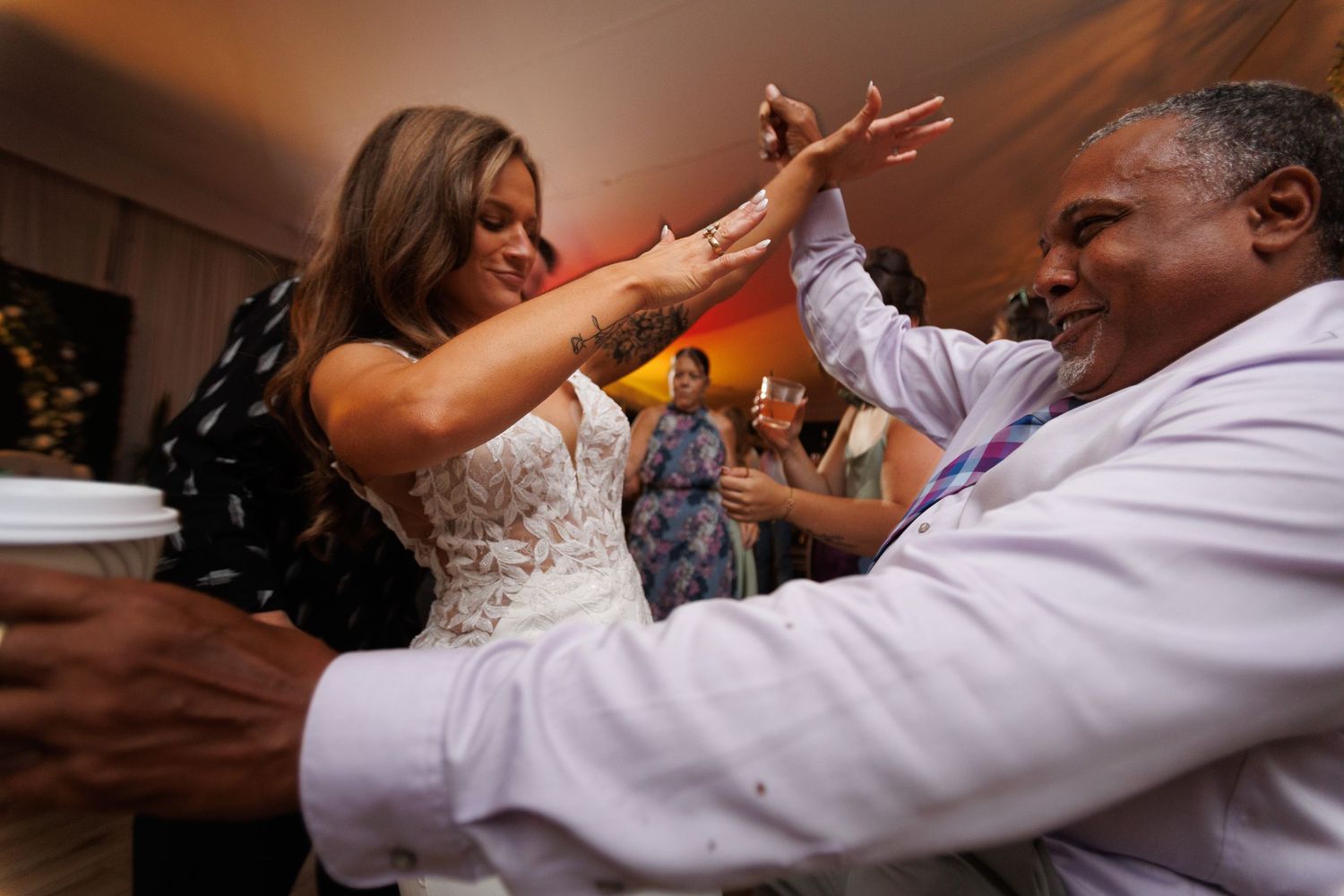 People enjoying a lively dance sequence at what appears to be a wedding reception or celebration event.