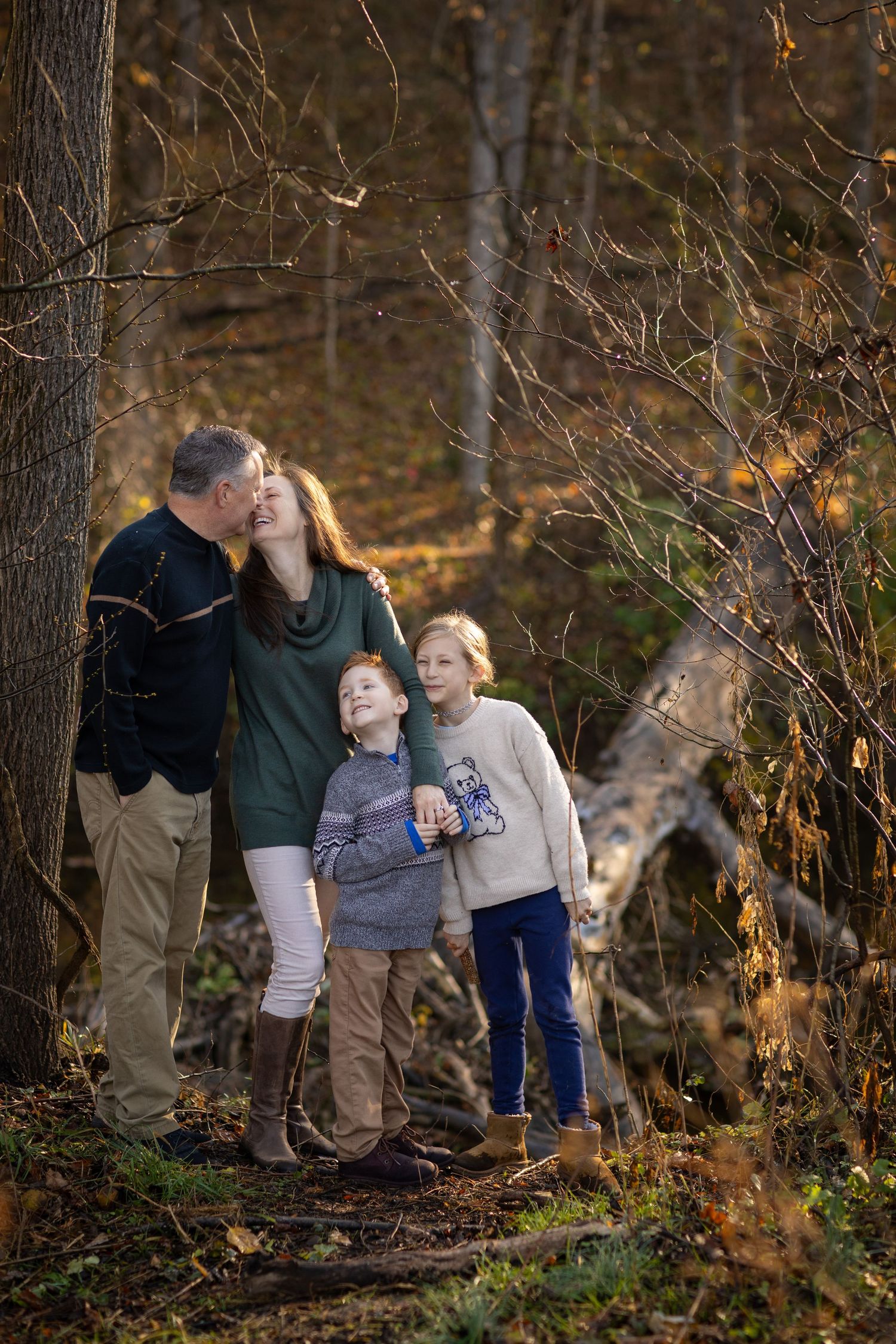 Family group walking together on autumn forest trail during golden hour.