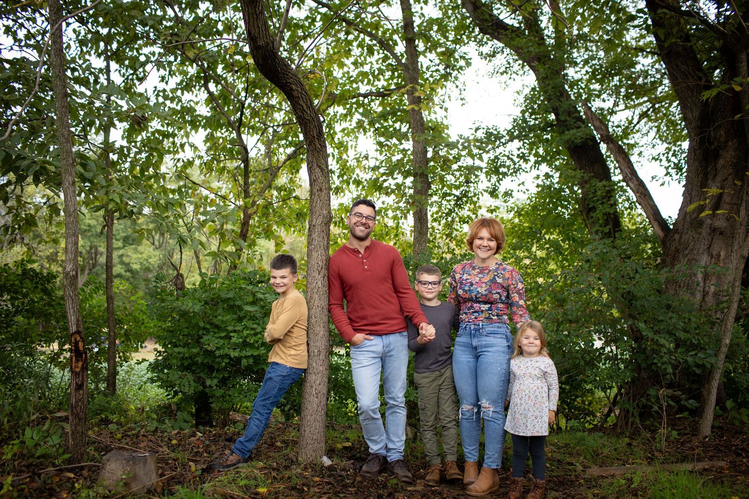 A group stands together in a lush wooded area during a casual outdoor photo session.