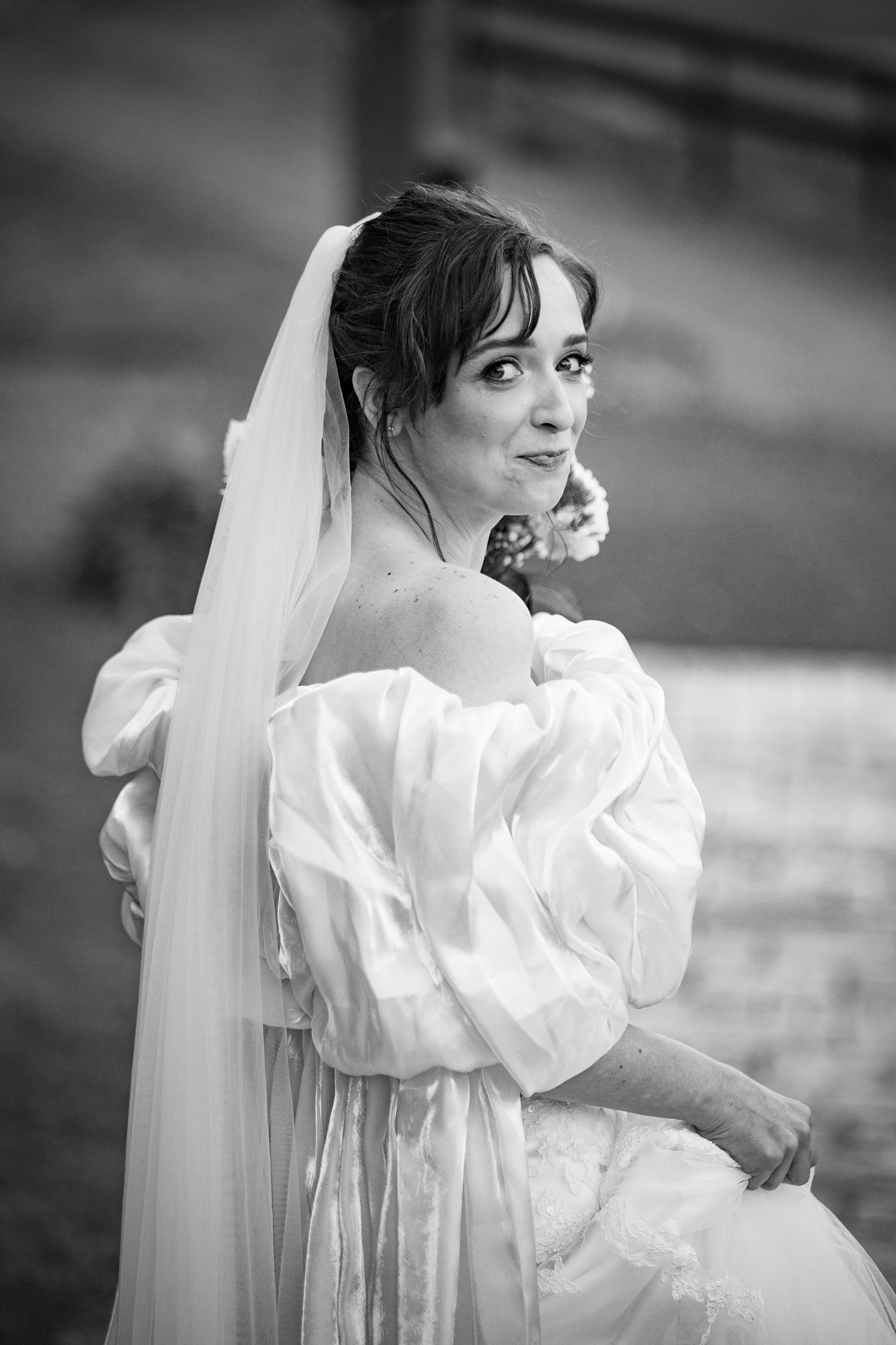 Black and white bridal portrait of bride in off-shoulder puff sleeve wedding gown with veil.