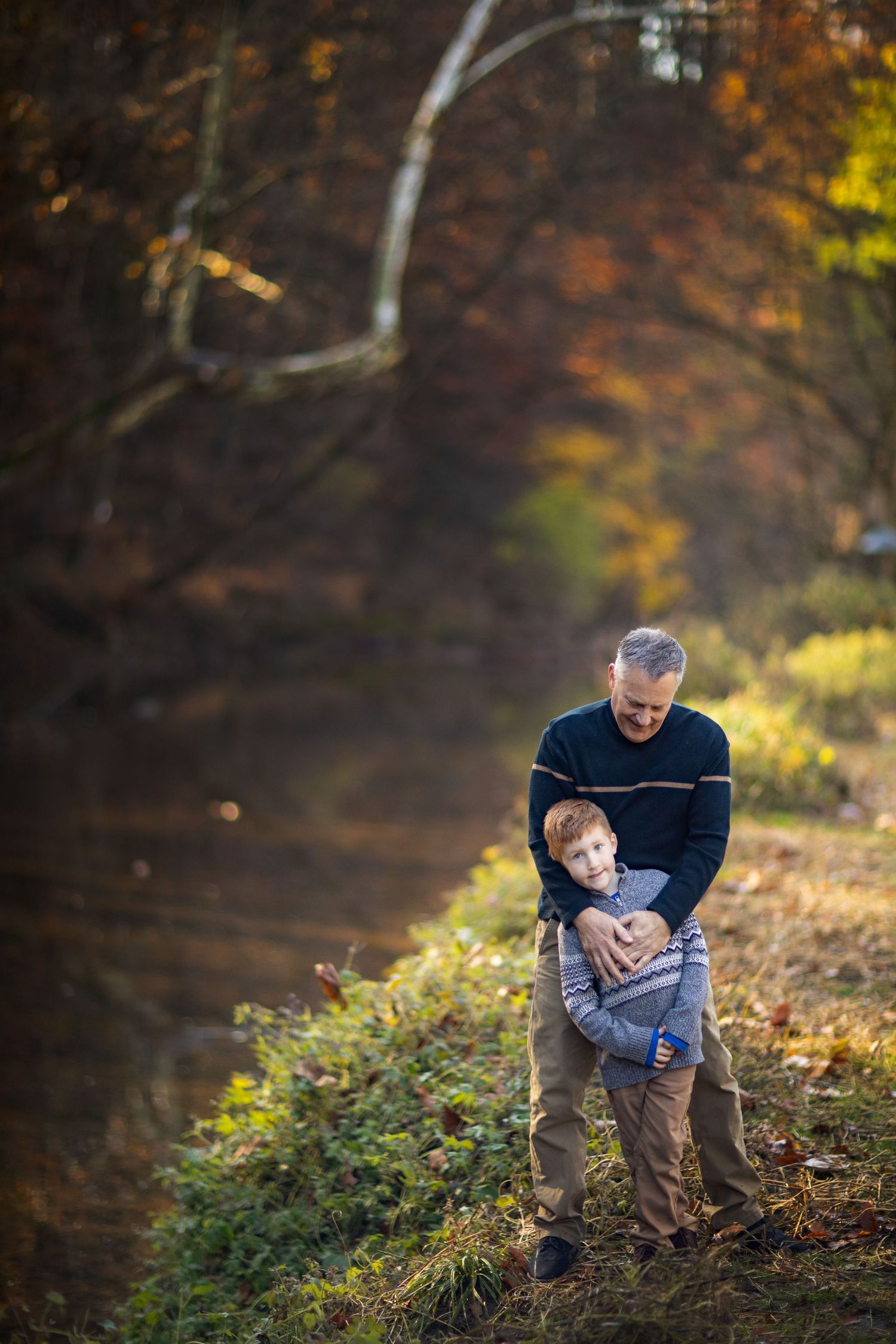 Playful interaction between two people on a wooded hillside during golden hour in autumn.