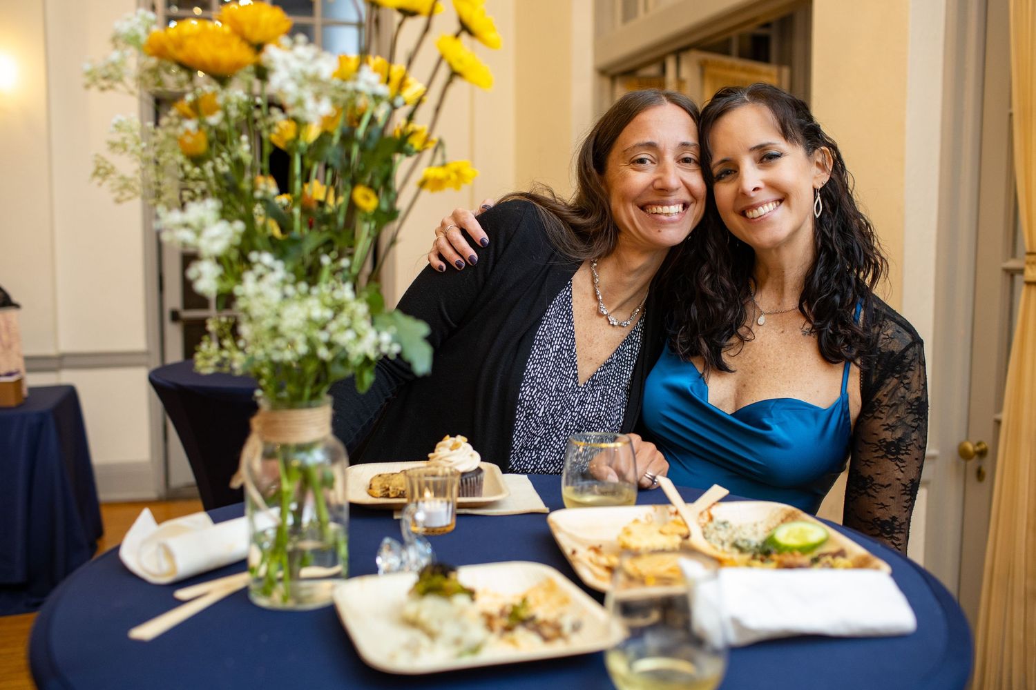 Elegant wedding reception with yellow floral centerpieces and guests dining at tables.