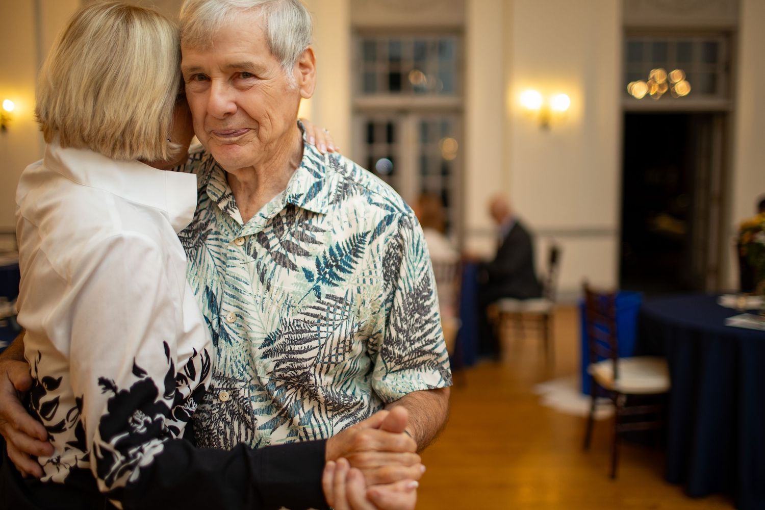 Indoor event showing attendees in casual tropical attire enjoying conversation.